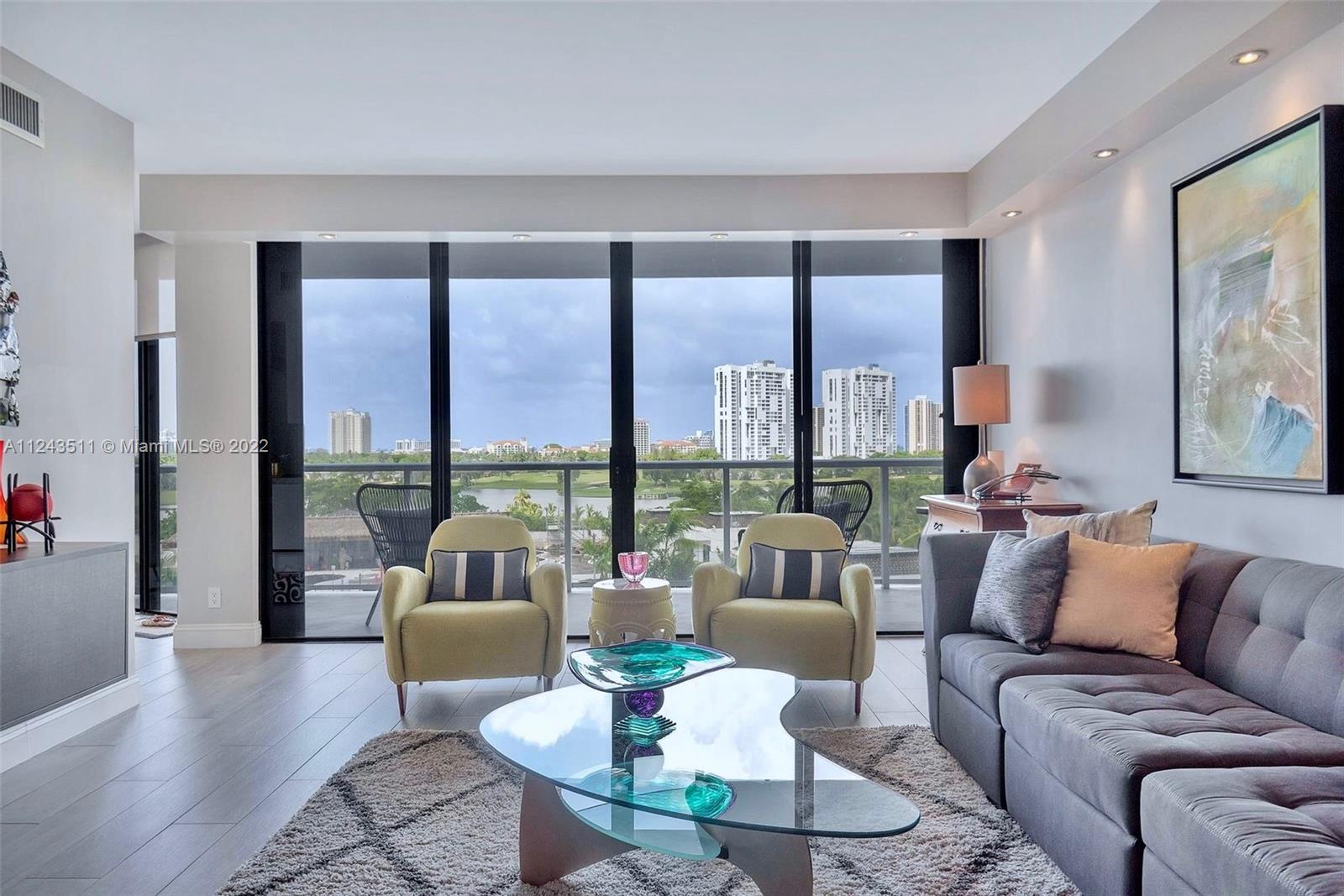 View of the living room and balcony from the front door with Turnberry Isle Country Club beyond.