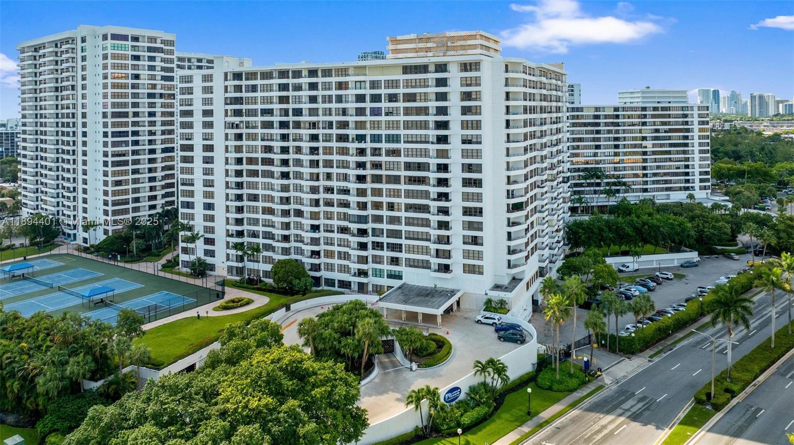 Photo of 600 Three Islands Blvd  #317, Hallandale Beach, Florida, 33009 - View of front entrance of building 600, valet area, unground parking entrance & sports courts