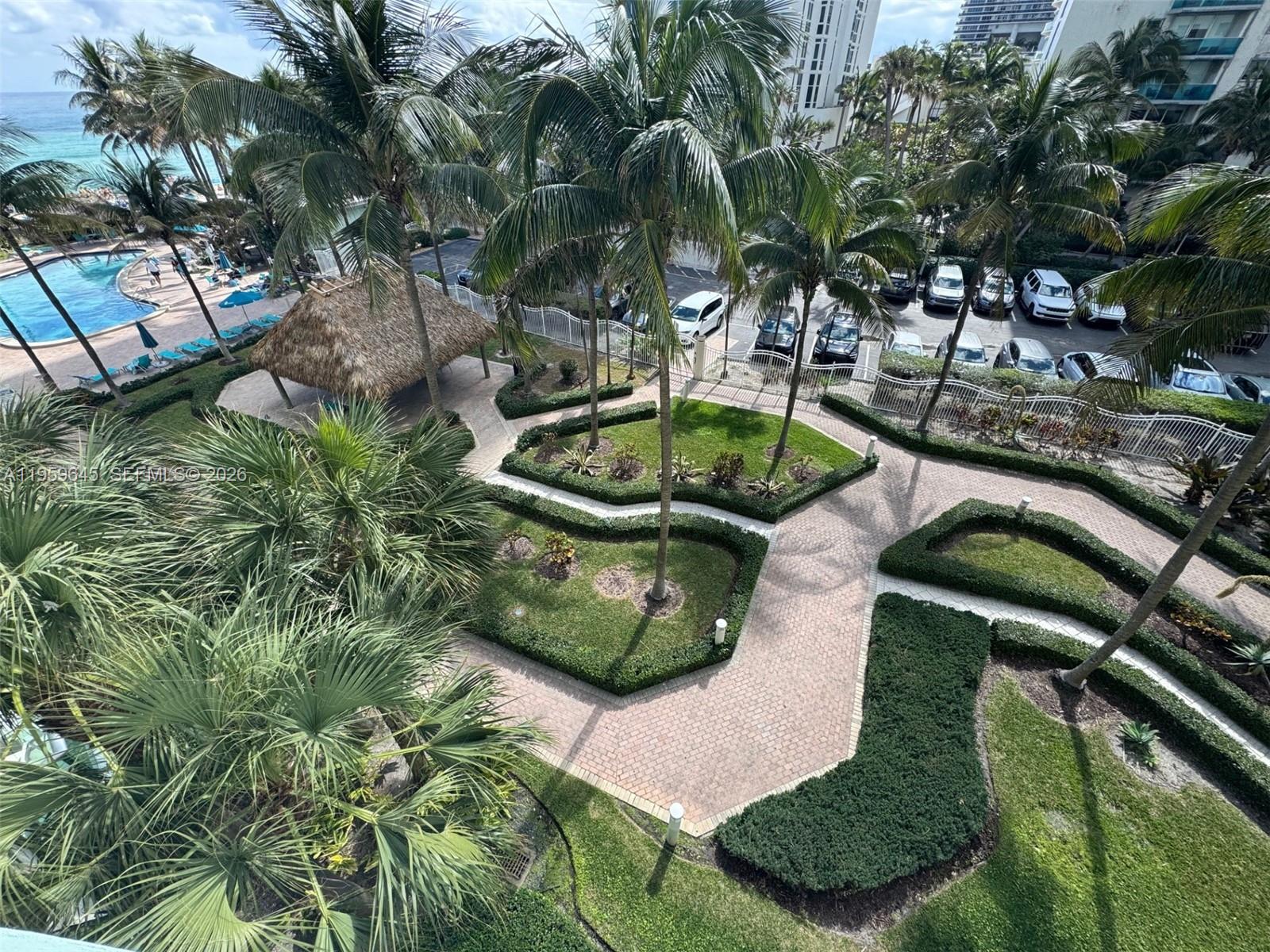 Photo of 3901 Ocean Dr #4J, Hollywood, Florida, 33019 - Pool area, beach access with Tiki Hut and lush landscaping.