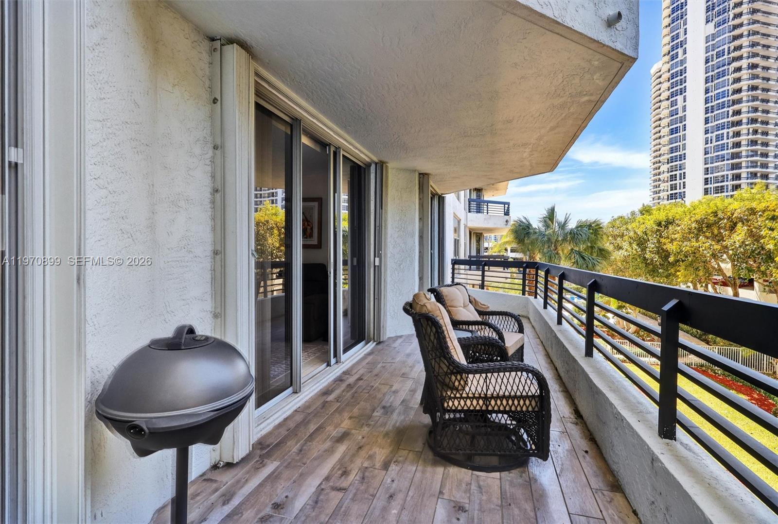Photo of 3500 Mystic Pointe Dr  #302, Aventura, Florida, 33180 - One of the largest balconies in the building, offering beautiful lush green views and plenty of space for outdoor seating and entertaining.