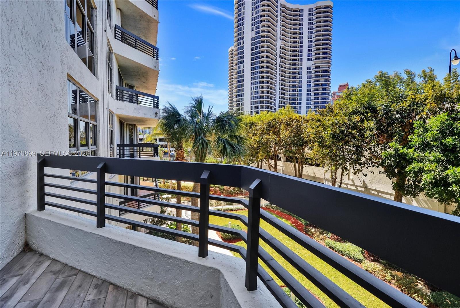 Photo of 3500 Mystic Pointe Dr  #302, Aventura, Florida, 33180 - One of the largest balconies in the building, offering beautiful lush green views and plenty of space for outdoor seating and entertaining.