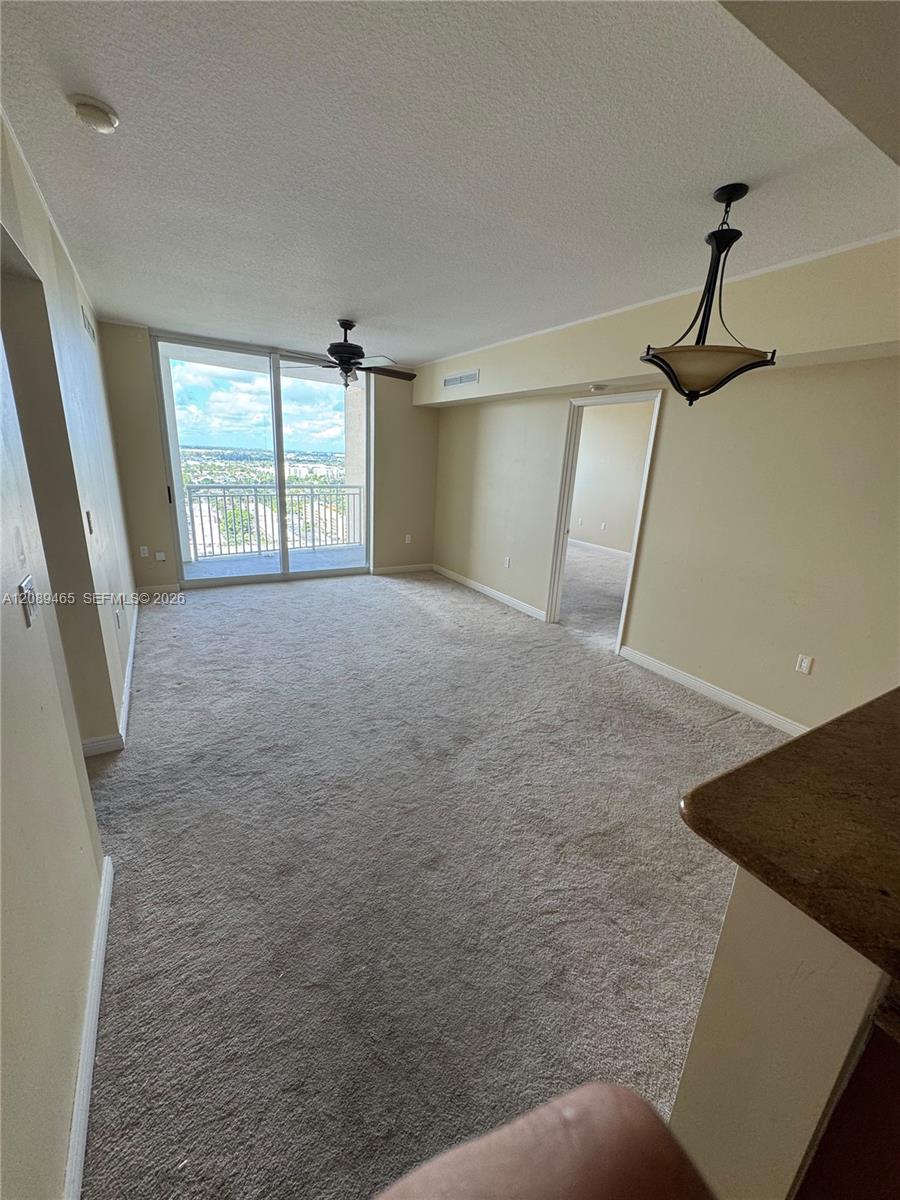 Living Dining area featuring neutral carpeting, a ceiling fan, a hanging pendant light fixture, and a glass sliding door leading to an exterior balcony