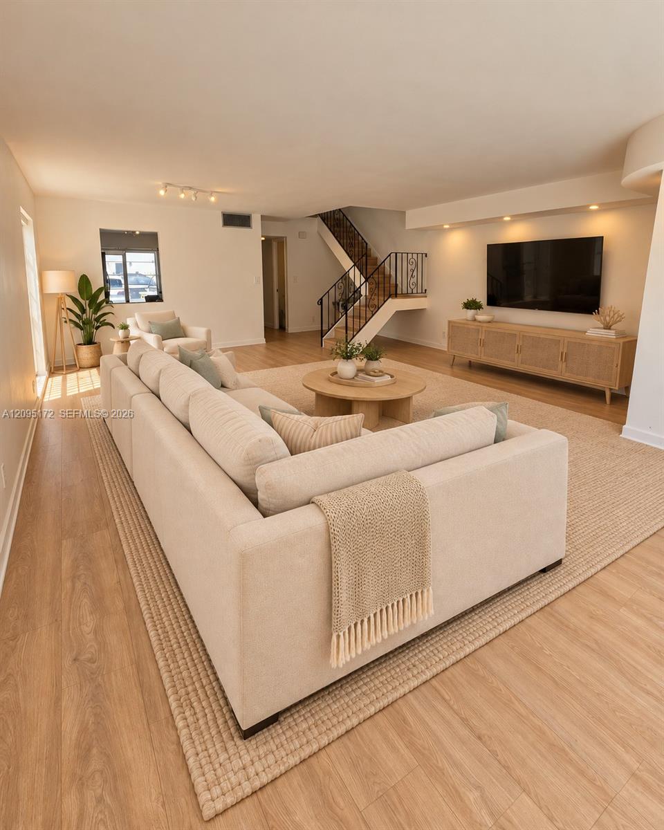 Wood-finish flooring, full-height built-in cabinetry, multi-pane window with exterior shade, and triple-bulb ceiling light fixture