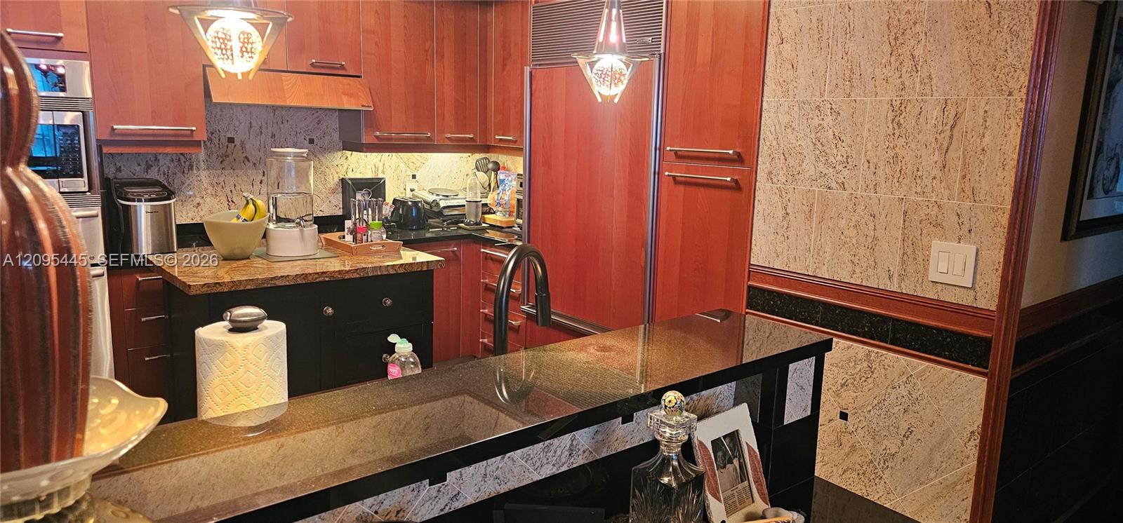Kitchen featuring cherry-wood cabinetry, stone countertops, panel-ready refrigerator, and black metal faucet fixtures