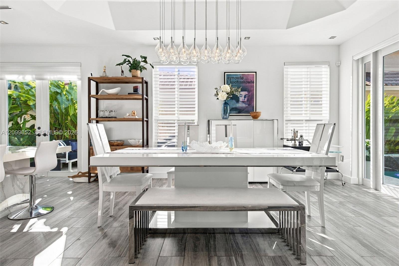 Dining area featuring a recessed tray ceiling, wood-finish tile flooring, and a multi-pendant chandelier