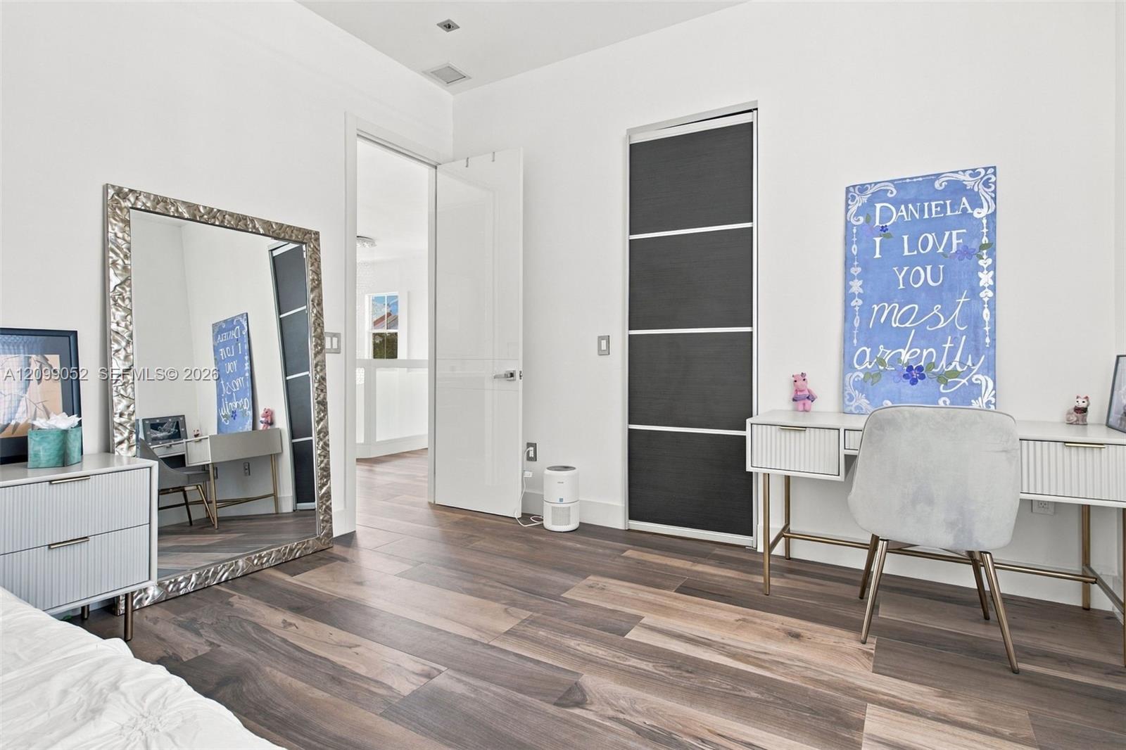 Room featuring wood-finish flooring, recessed ceiling lighting, and a closet with sliding dark-toned panels and metallic trim
