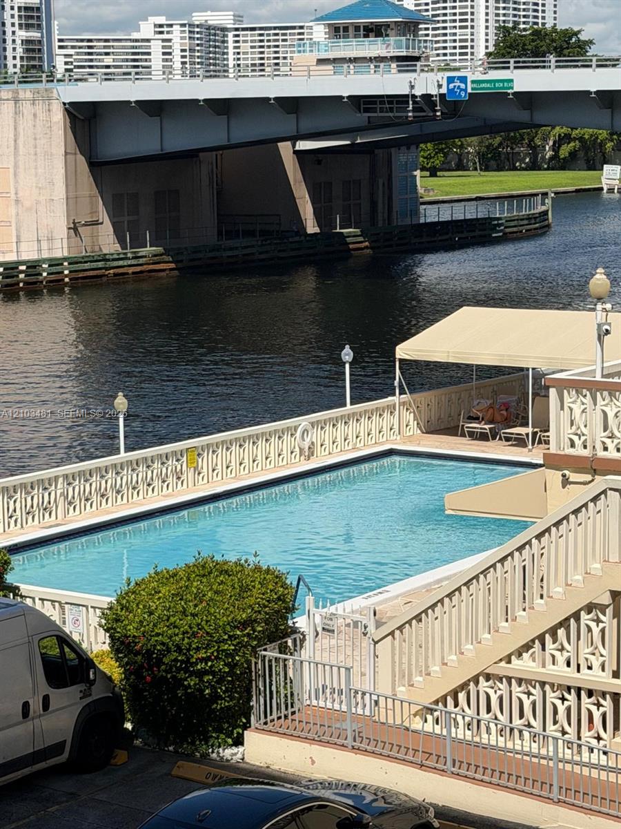 Waterfront swimming pool featuring decorative concrete screen walls, a metal-framed canopy, integrated pedestal lighting, and direct bulkhead access to the waterway