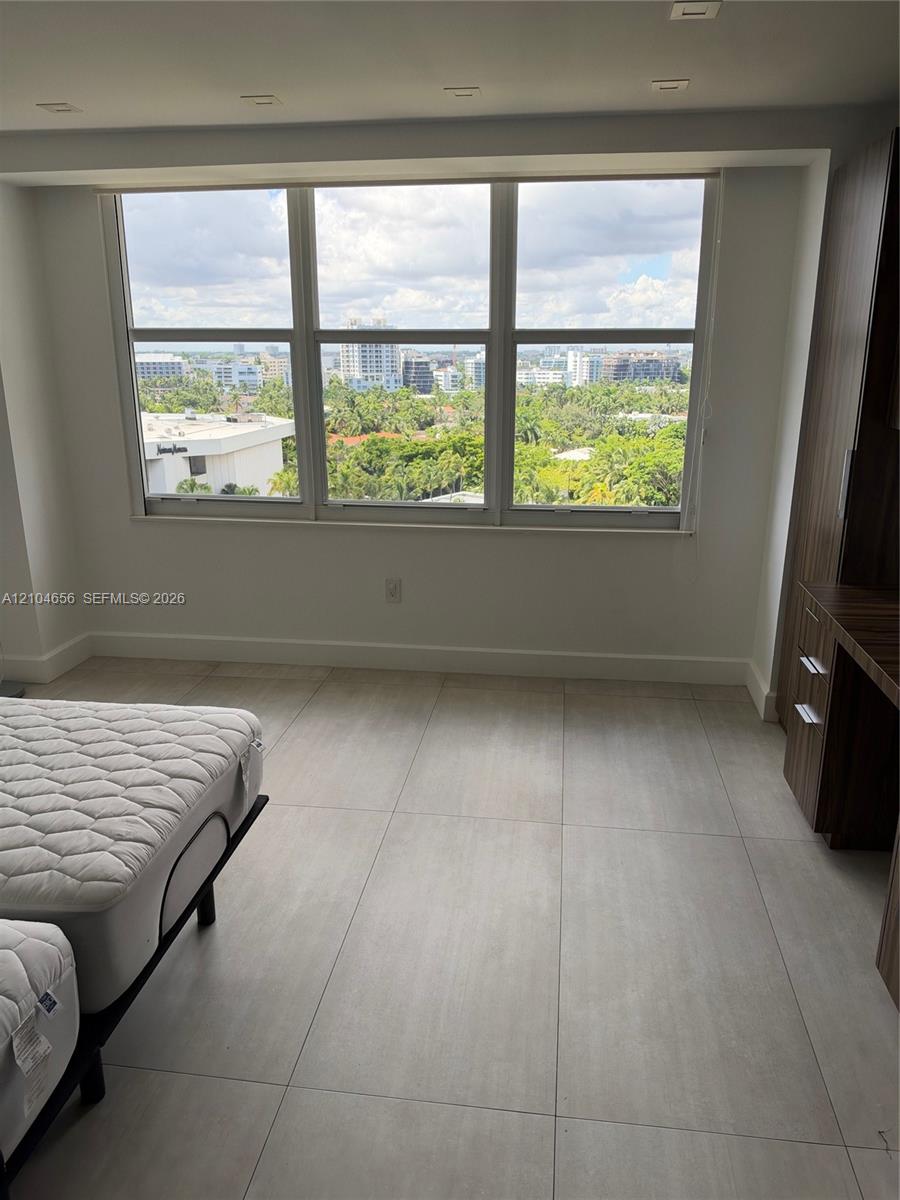 Large multi-pane window with expansive urban and landscape scenery, neutral ceramic tile flooring, and integrated wood-finish built-in cabinetry featuring drawer storage