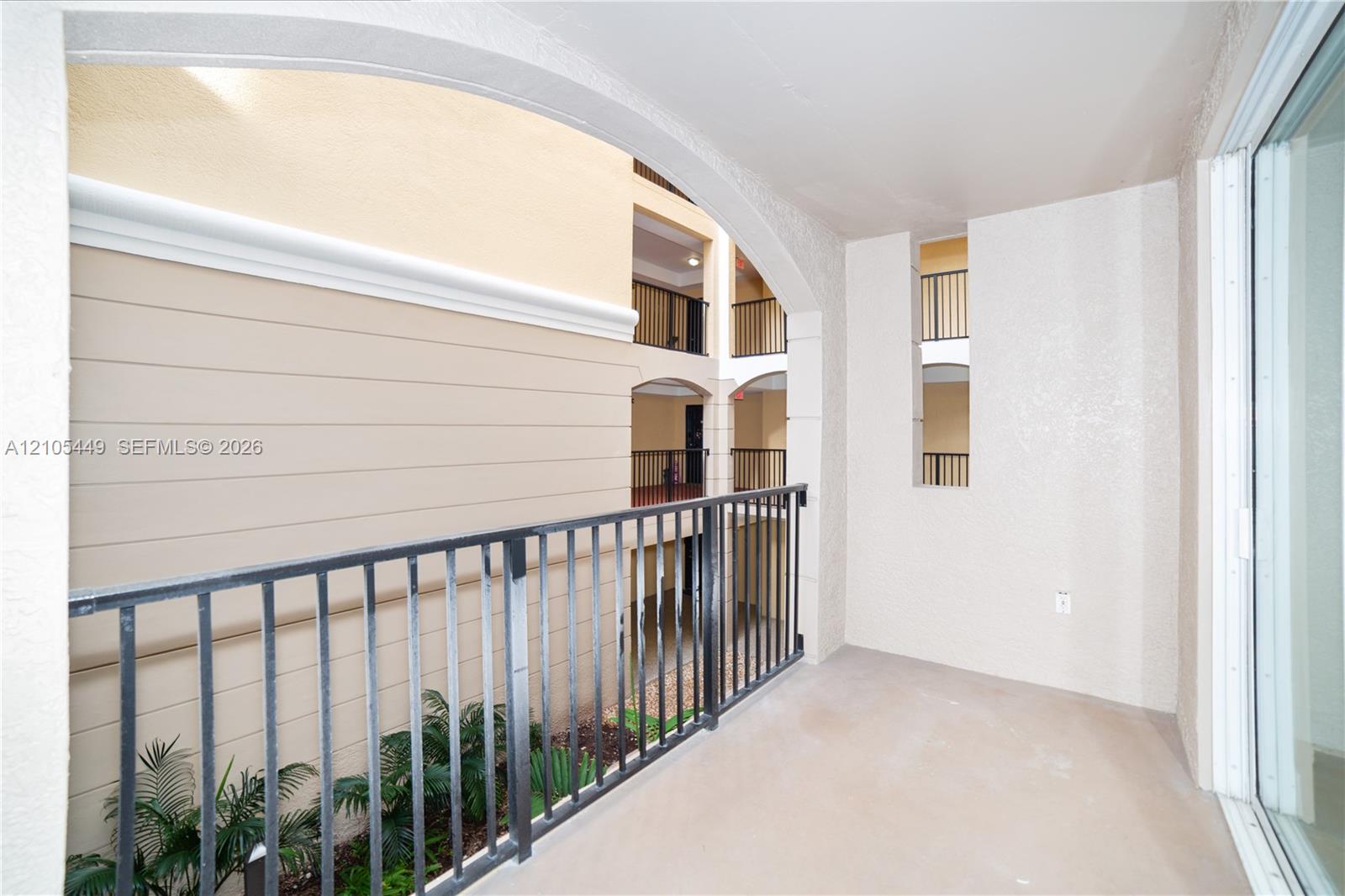 Balcony featuring a concrete floor, black metal railing, and textured wall finish