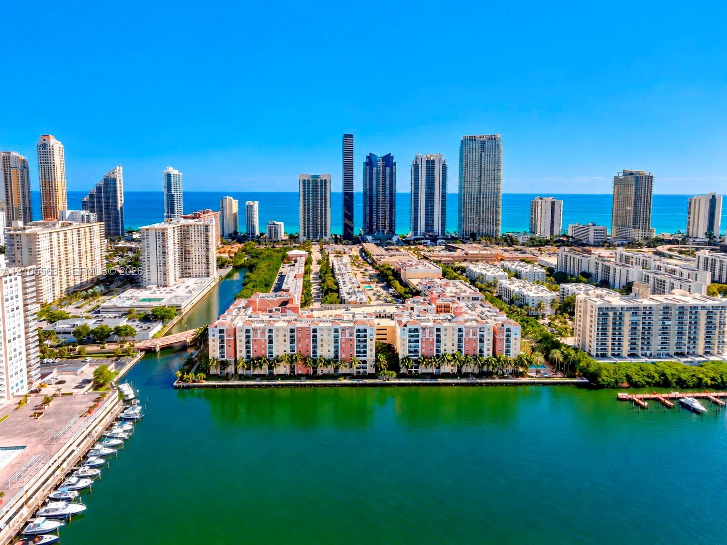Coastal skyline featuring multiple high-rise buildings, a marina with docked boats, and waterways
