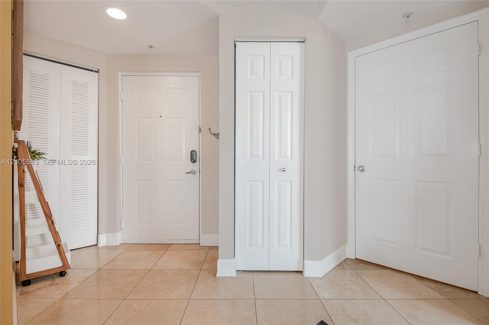 Tiled flooring with a white paneled door, louvered bi-fold door, and paneled bi-fold door