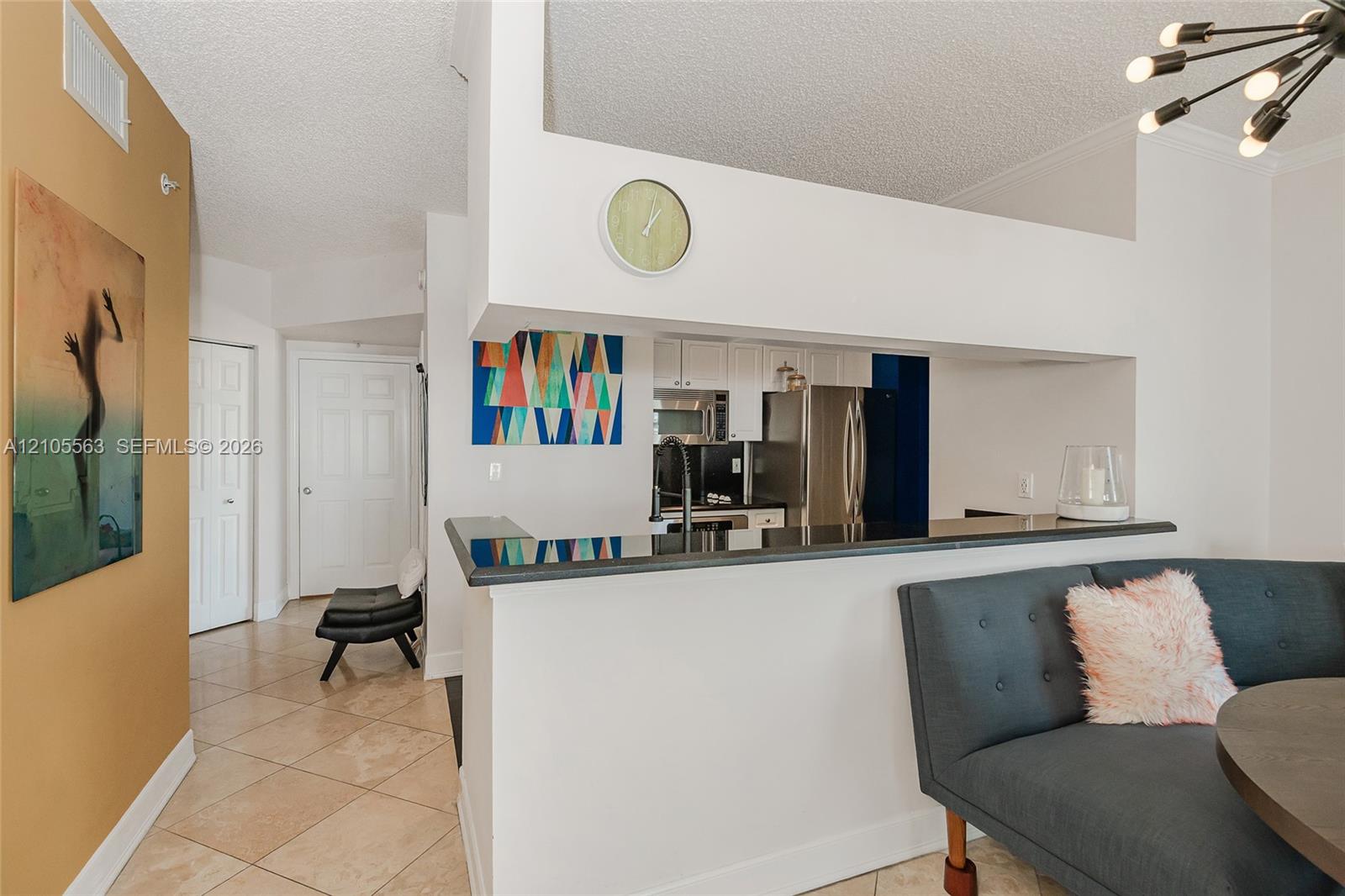 Kitchen pass-through with dark countertops, white cabinetry, and stainless steel appliances