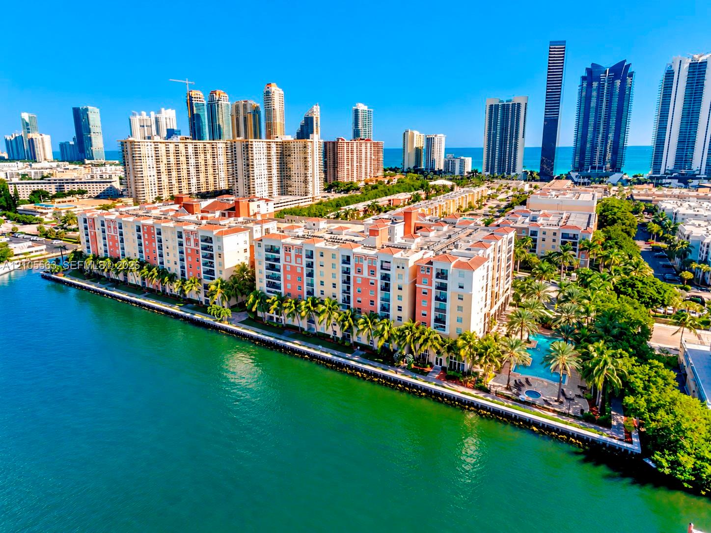 Waterfront property with multiple residential buildings, private balconies, and an outdoor swimming pool