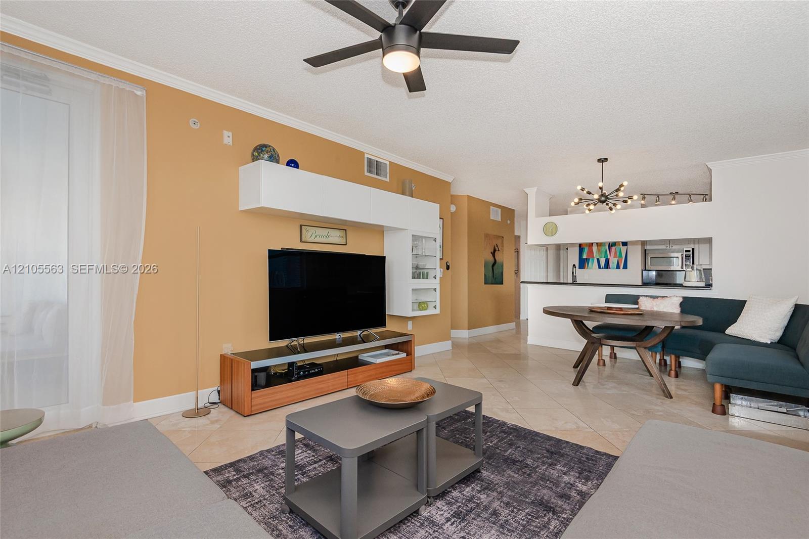 Open-concept living area featuring a built-in media center, ceiling fan, and tile flooring