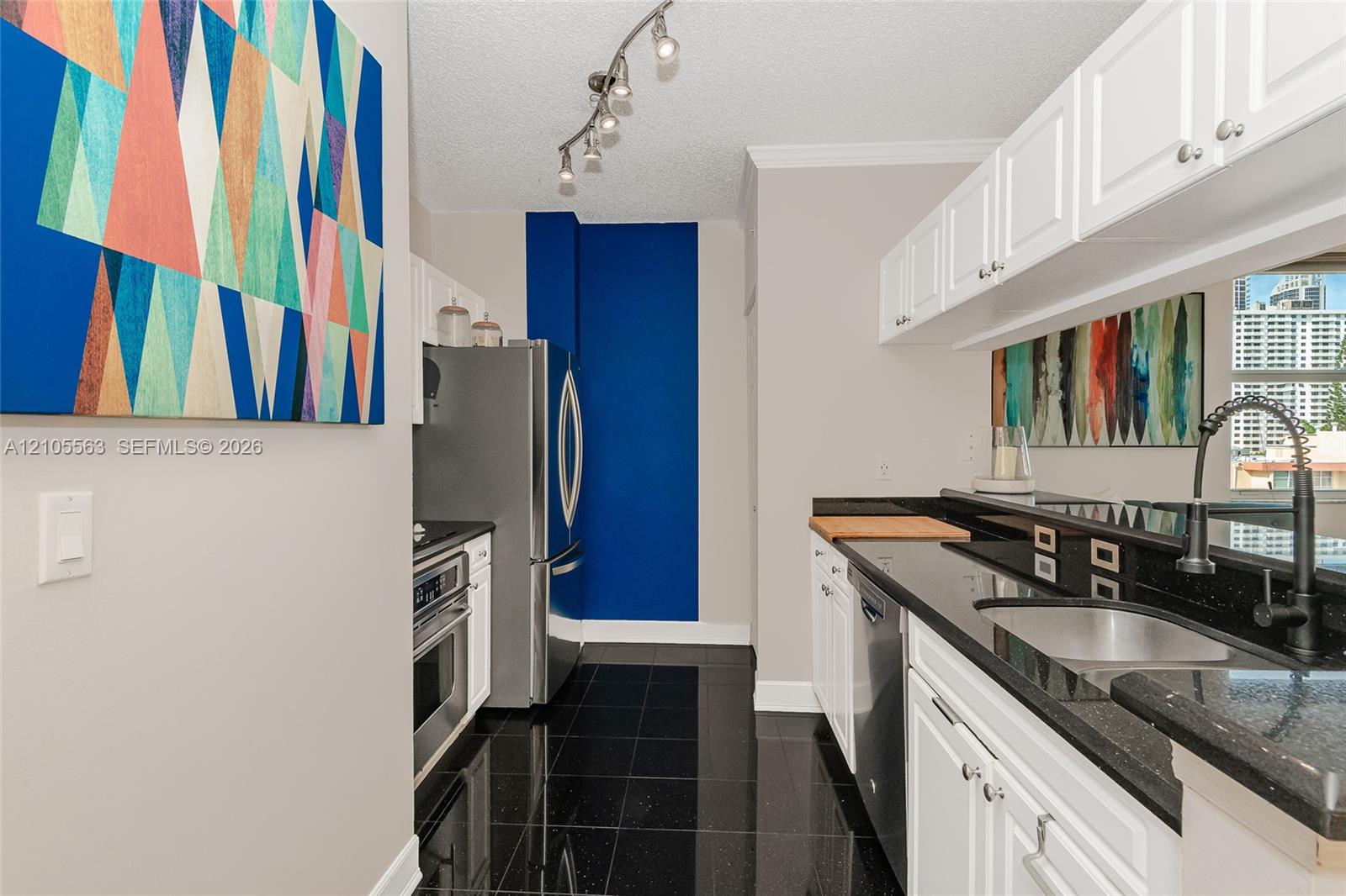 Kitchen featuring white cabinetry, black countertops, a stainless steel refrigerator, and a stainless steel oven