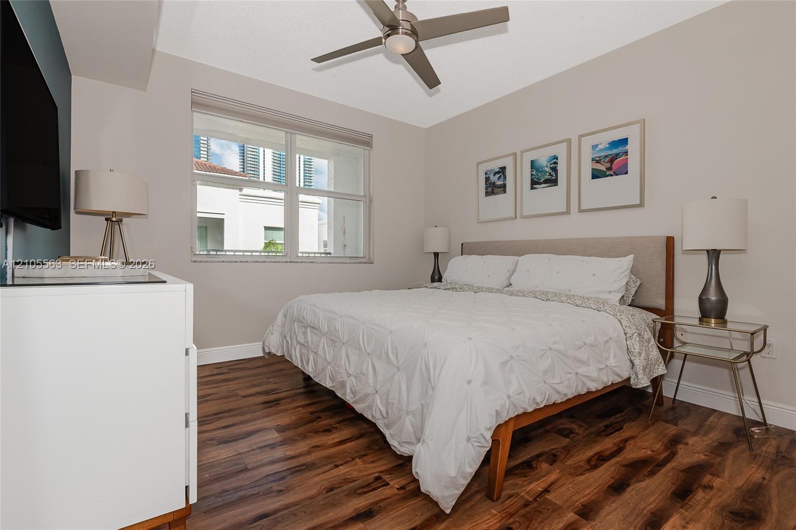 Wood-finish flooring with a neutral wall color, overhead ceiling fan, and a large window