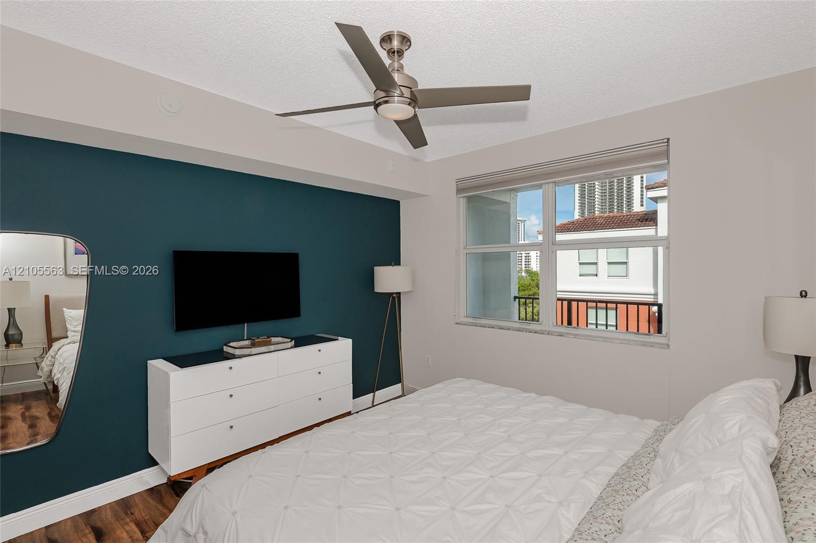 Contemporary bedroom with a window, wood-finish flooring, and a ceiling fan