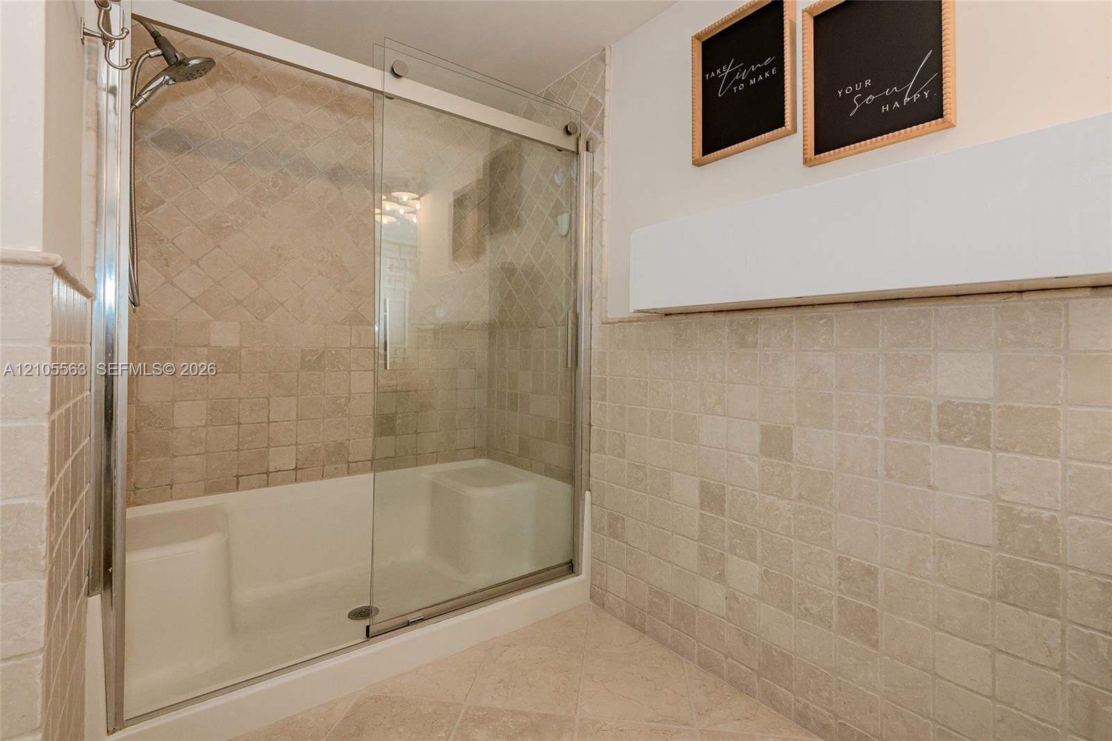 Shower enclosure with sliding glass door, integrated seating, and full-height tile surround