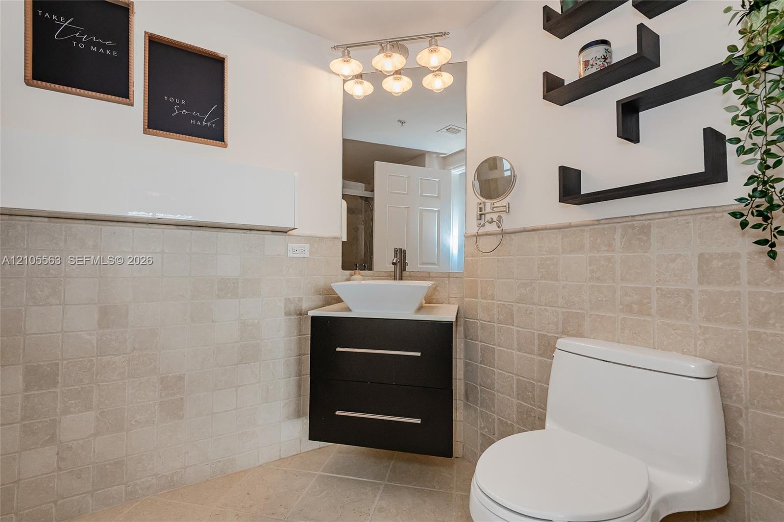 White vanity with a rectangular vessel sink, vanity light fixture, and wall-mounted shelves