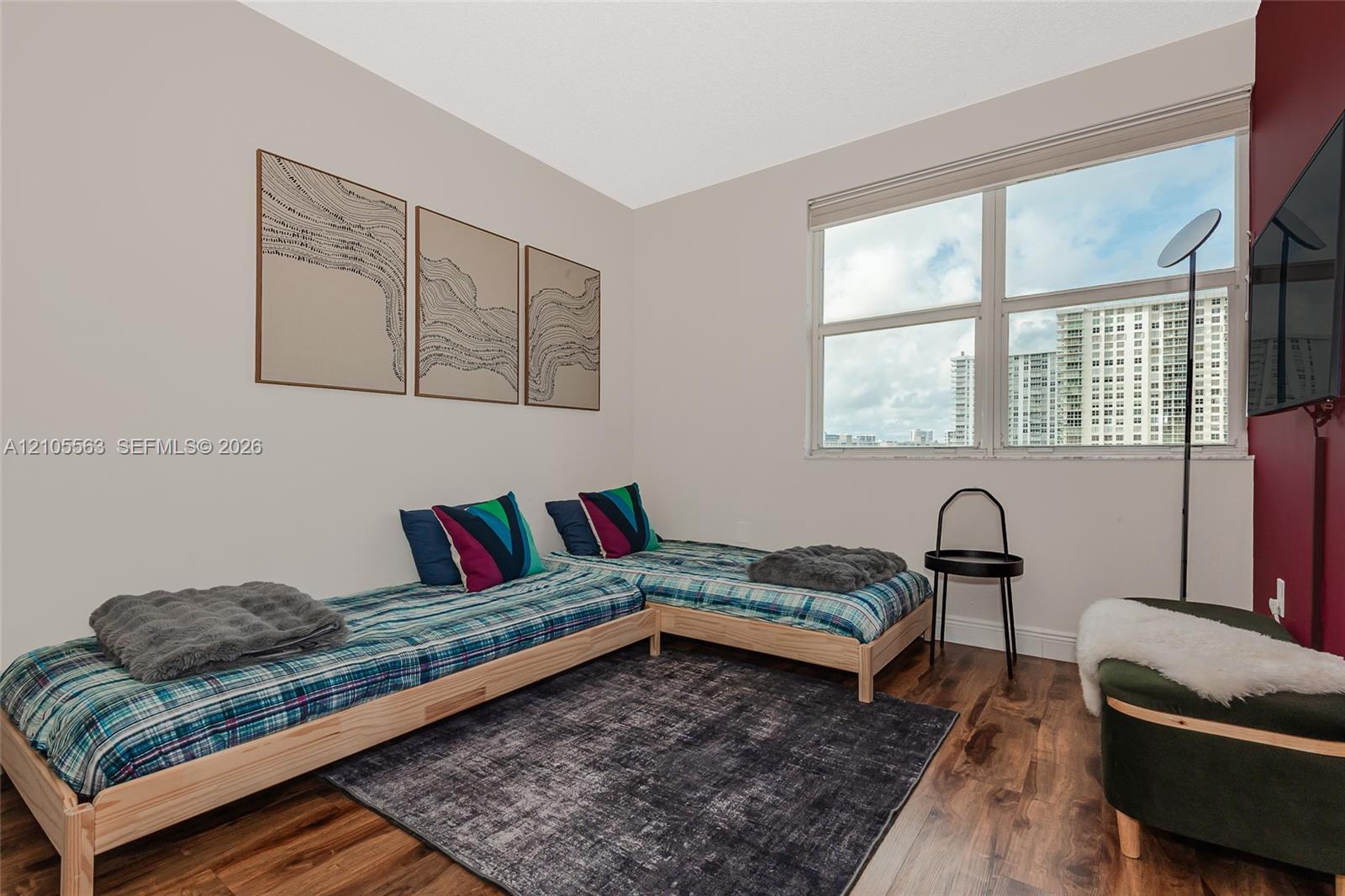 Wood-finish flooring, white walls, and a large window with roller shades
