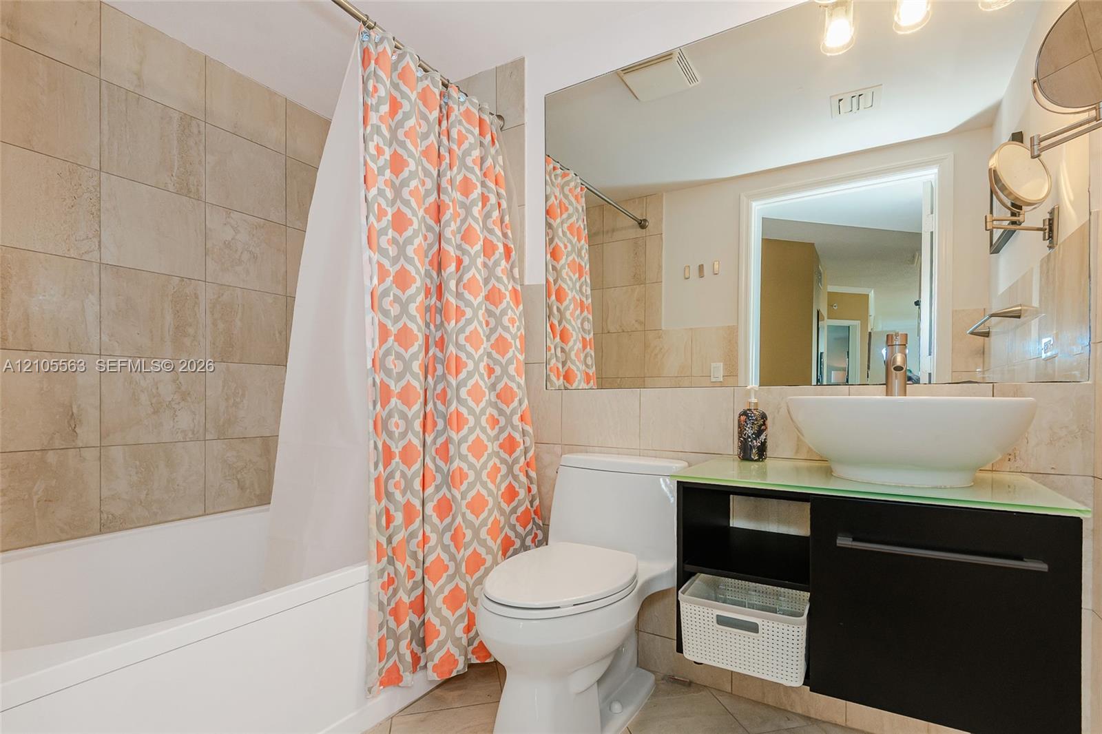 Bathroom featuring a ceramic tile shower surround, a white bathtub, and a modern vanity with a vessel sink and glass countertop