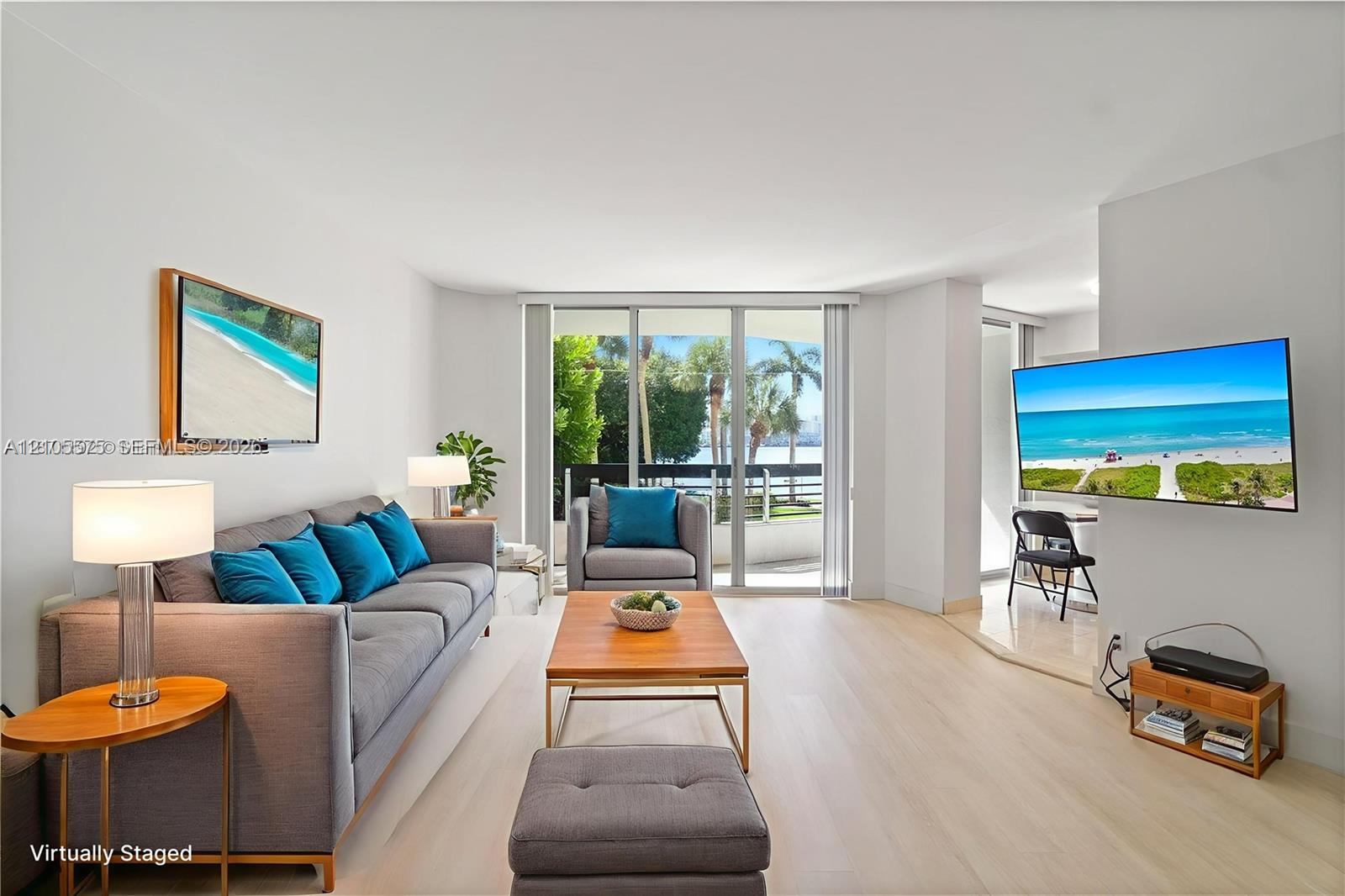 Spacious living room featuring an open-concept kitchen and direct access to a private balcony, creating a bright and inviting living space at Mystic Pointe in Aventura.
