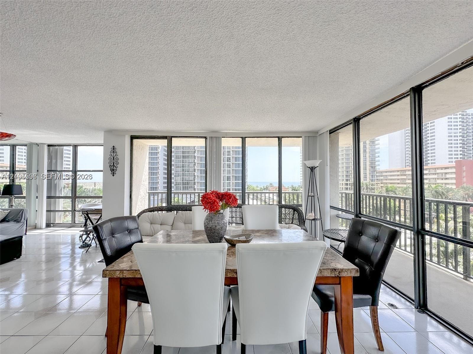 Expansive sunroom featuring floor-to-ceiling windows, polished tile flooring, and integrated black metal railings