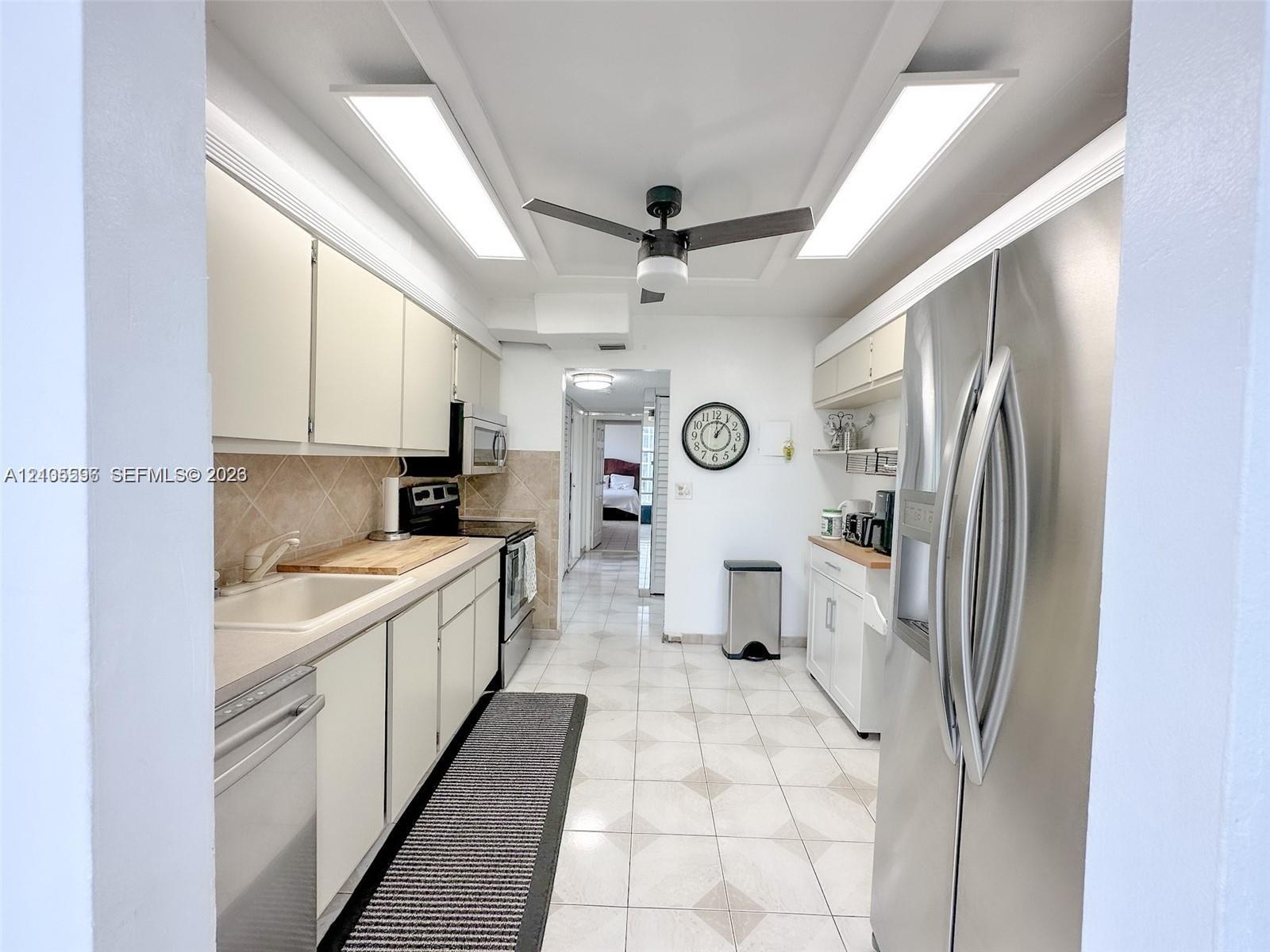 Kitchen featuring stainless steel appliances, neutral cabinetry, tile flooring, and dual overhead recessed lighting