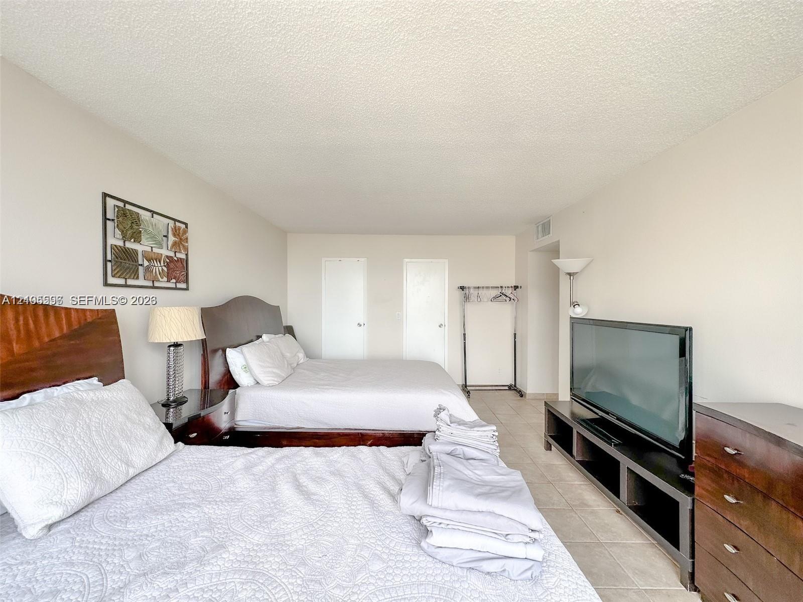 Neutral-toned bedroom with tile flooring and two interior doors