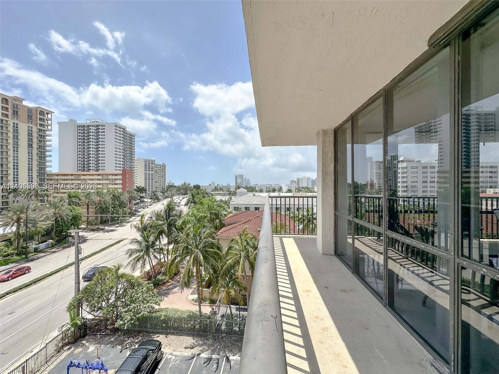 Covered balcony featuring metal railings and floor-to-ceiling glass paneling