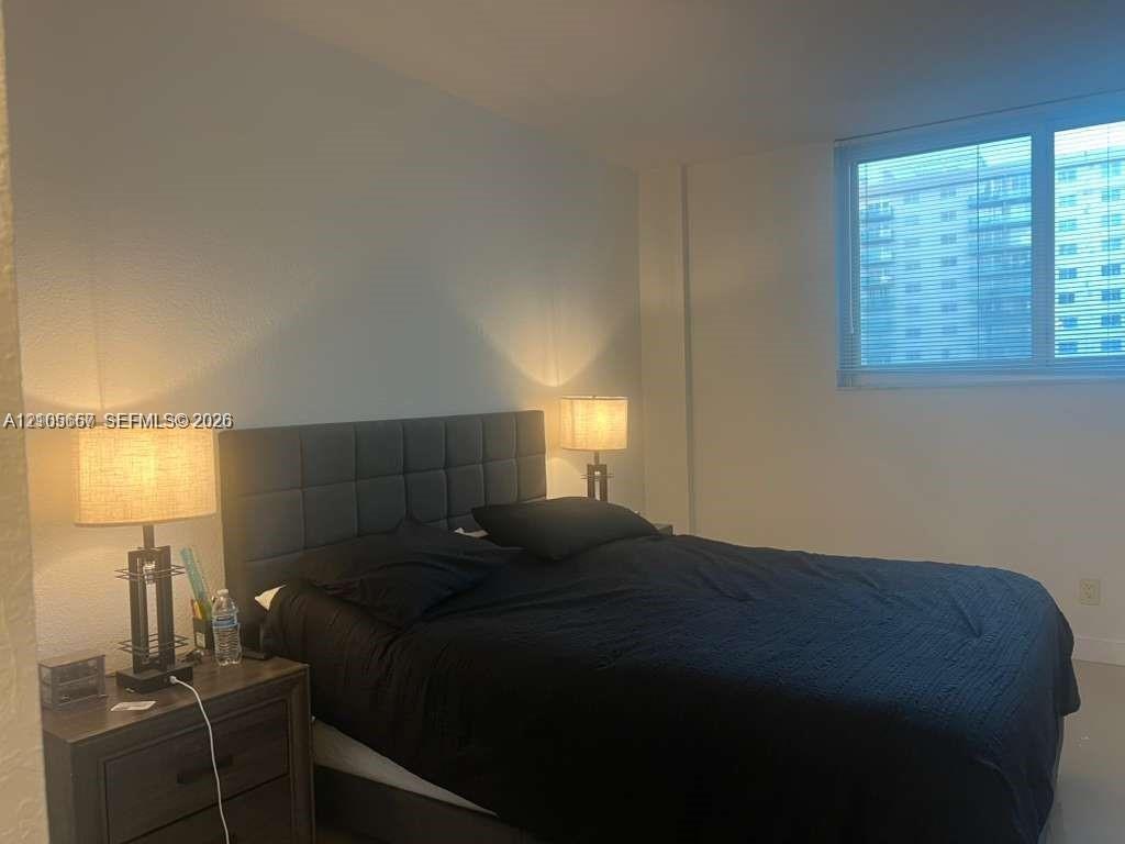 Large window with neutral-toned horizontal blinds and expansive wall space