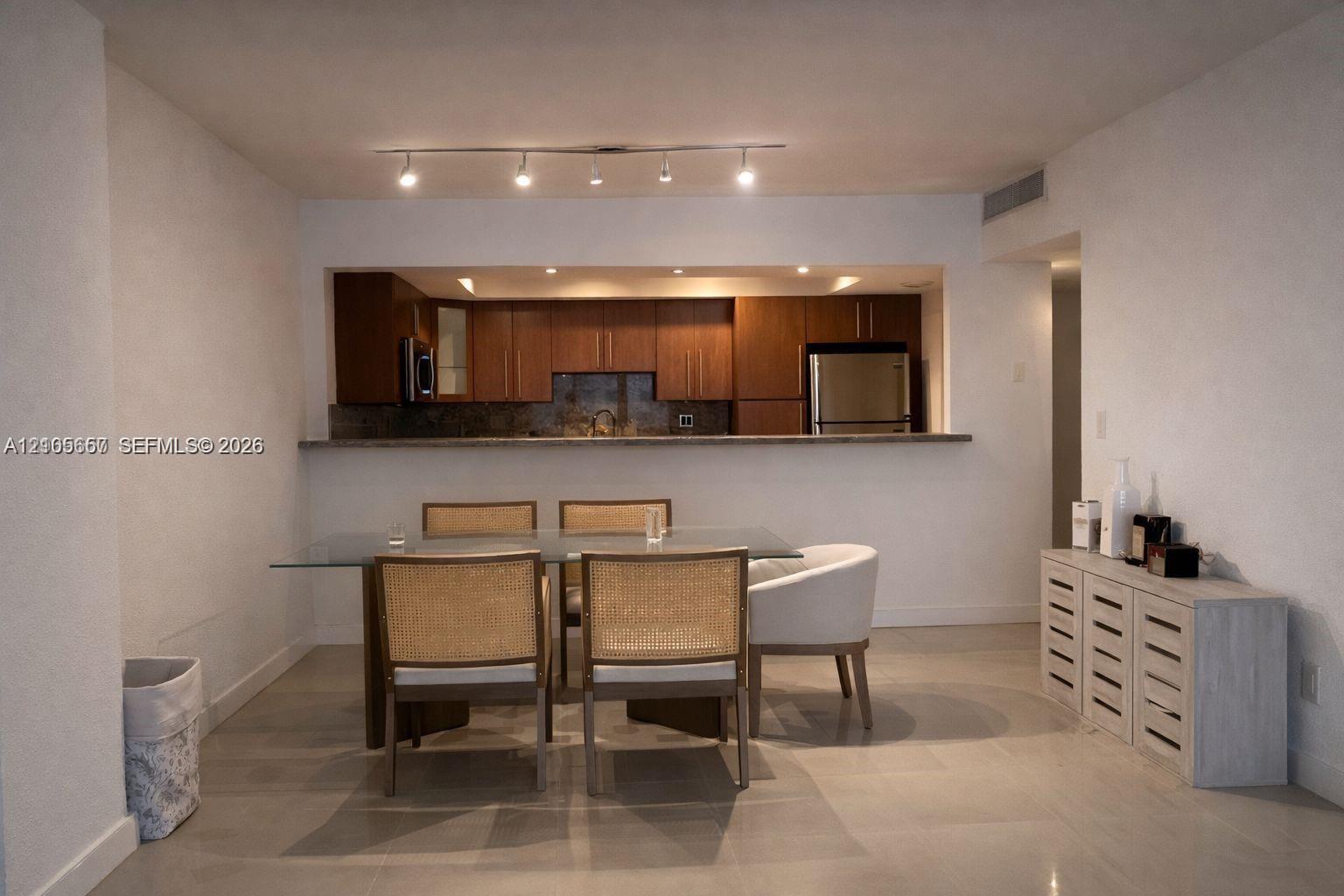 Kitchen featuring dark wood-finish cabinetry, stainless steel appliances, and a breakfast bar counter, illuminated by track lighting