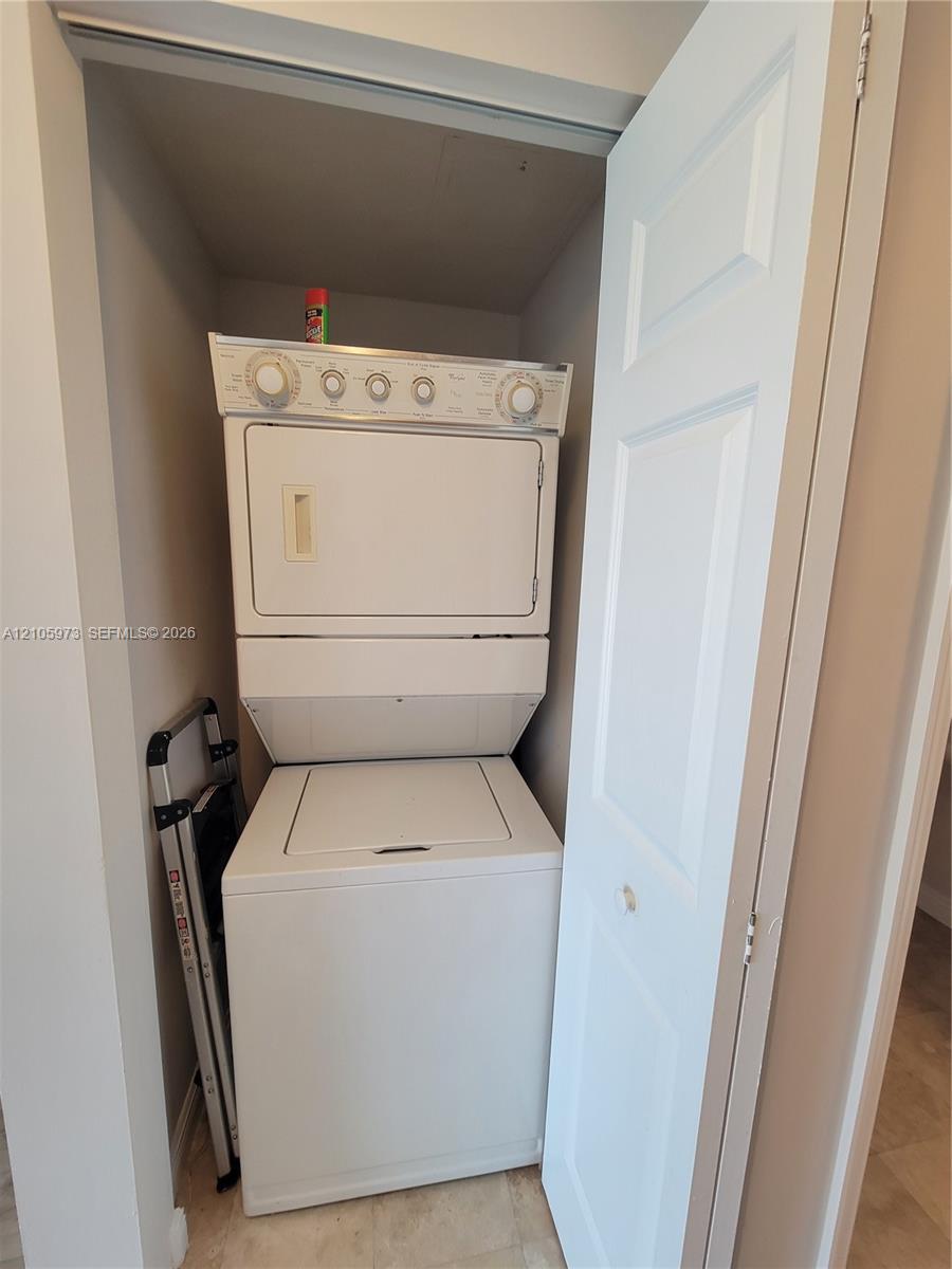 Stacked white washer and dryer unit housed within a dedicated laundry closet featuring a bi-fold door