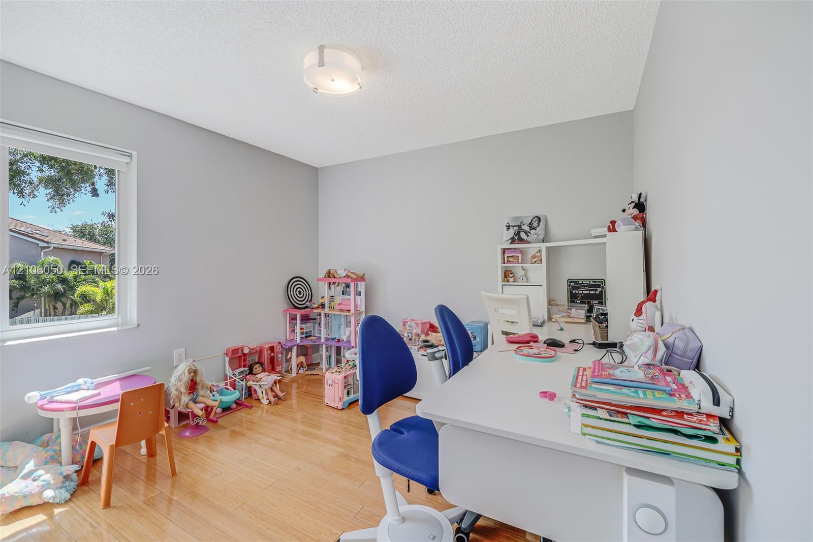 Room featuring wood-finish flooring, neutral wall paint, a single window, and a flush-mount ceiling light fixture