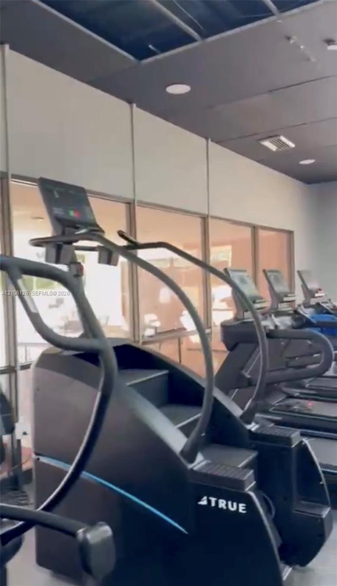 Fitness center featuring floor-to-ceiling glass windows, recessed ceiling lighting, and a dark-toned ceiling finish