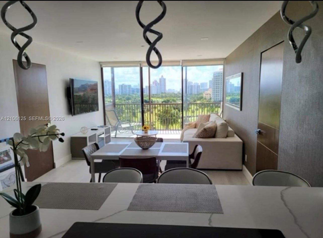 Floor-to-ceiling windows featuring exterior balcony access, stone-surface kitchen island, recessed lighting, and neutral-tone walls