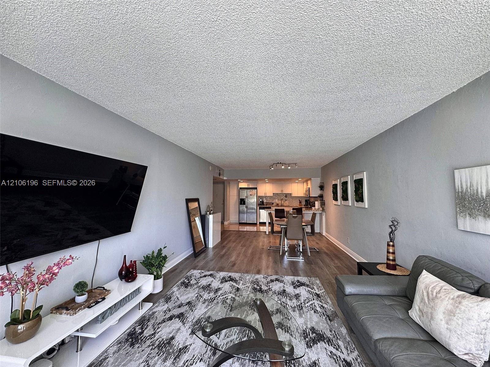 Open-concept layout featuring wood-finish flooring, recessed track lighting, and a breakfast bar