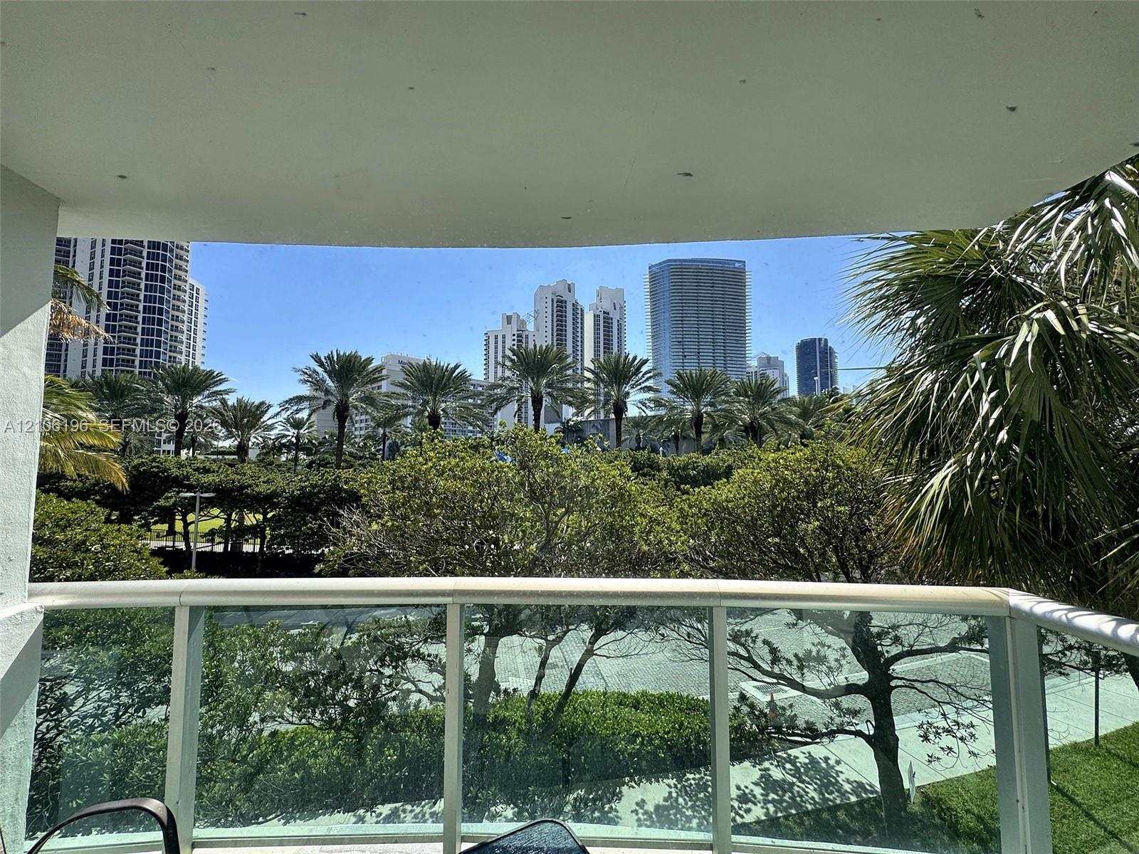 Covered terrace featuring glass panel railing and cityscape backdrop