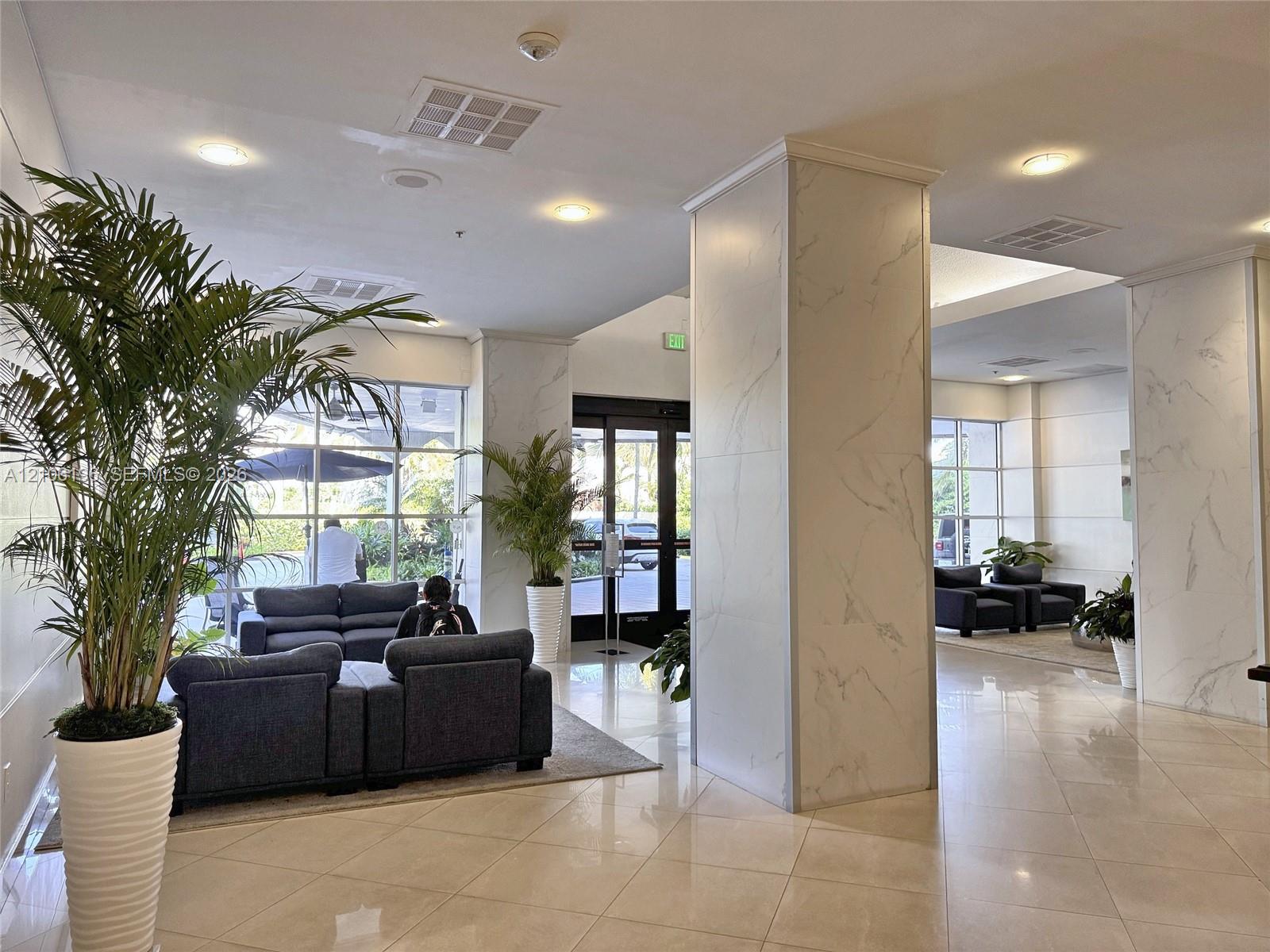 Lobby featuring stone-clad pillars, polished tile flooring, recessed ceiling lighting, and floor-to-ceiling glass windows
