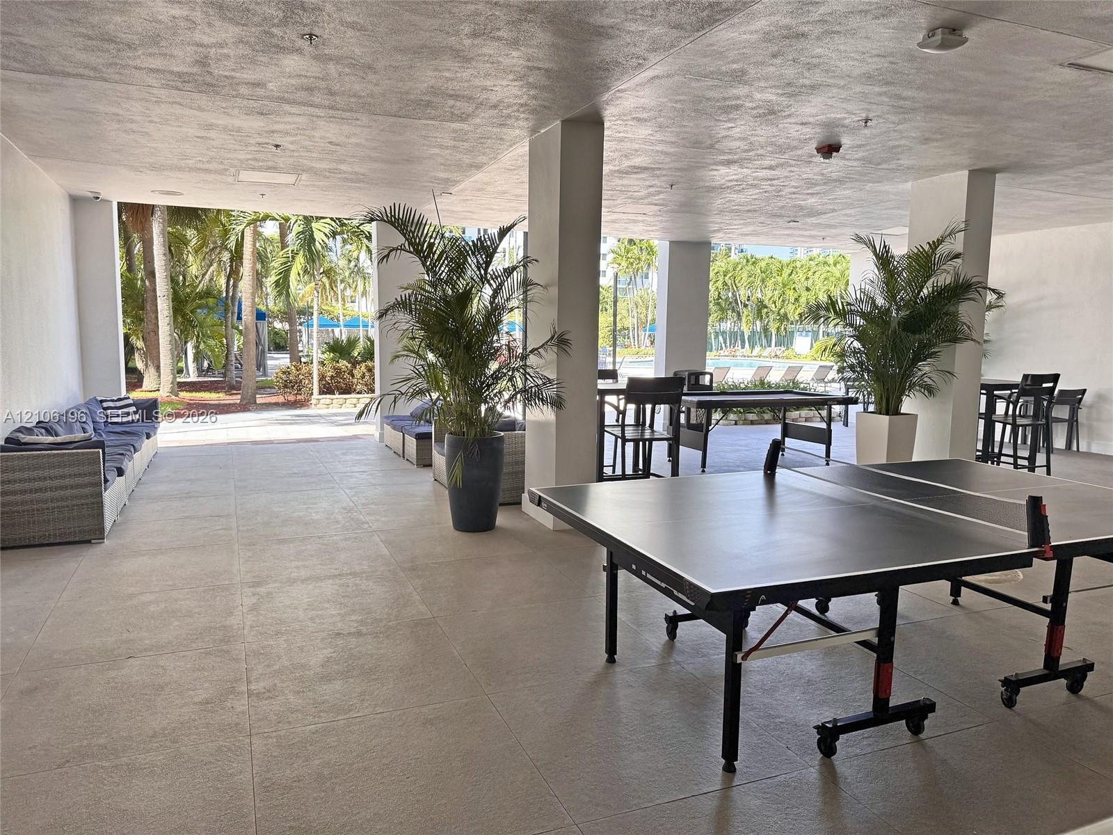 Covered outdoor recreation space featuring structural columns, large-format tile flooring, and expansive open-air access