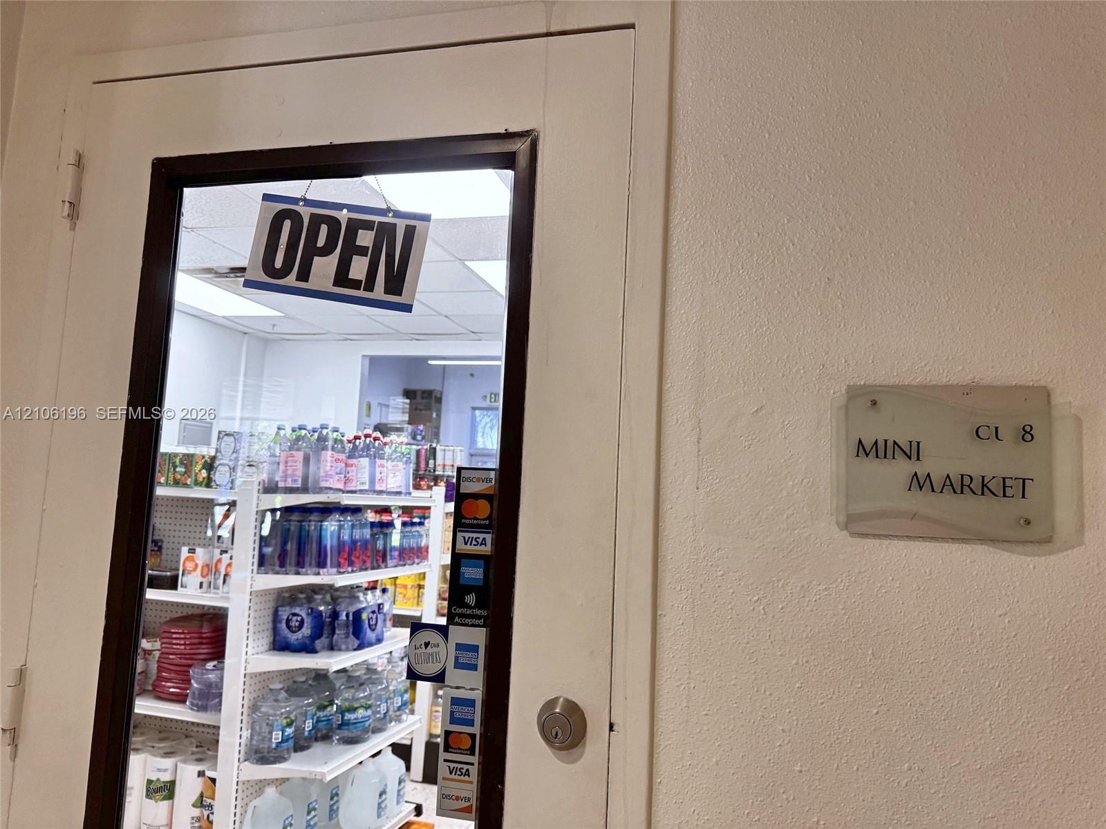 Commercial entrance featuring a glass-panel door with metal framing, a cylindrical deadbolt lock, and an integrated signage plaque