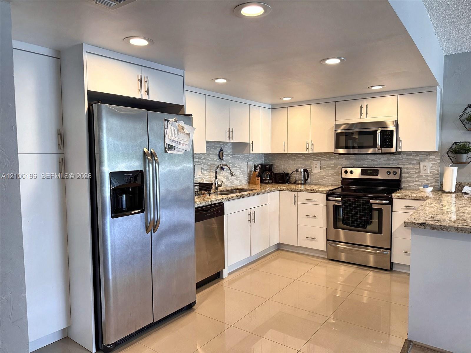 Kitchen featuring white cabinetry, stone-finish countertops, stainless steel appliances, a tile backsplash, and recessed lighting