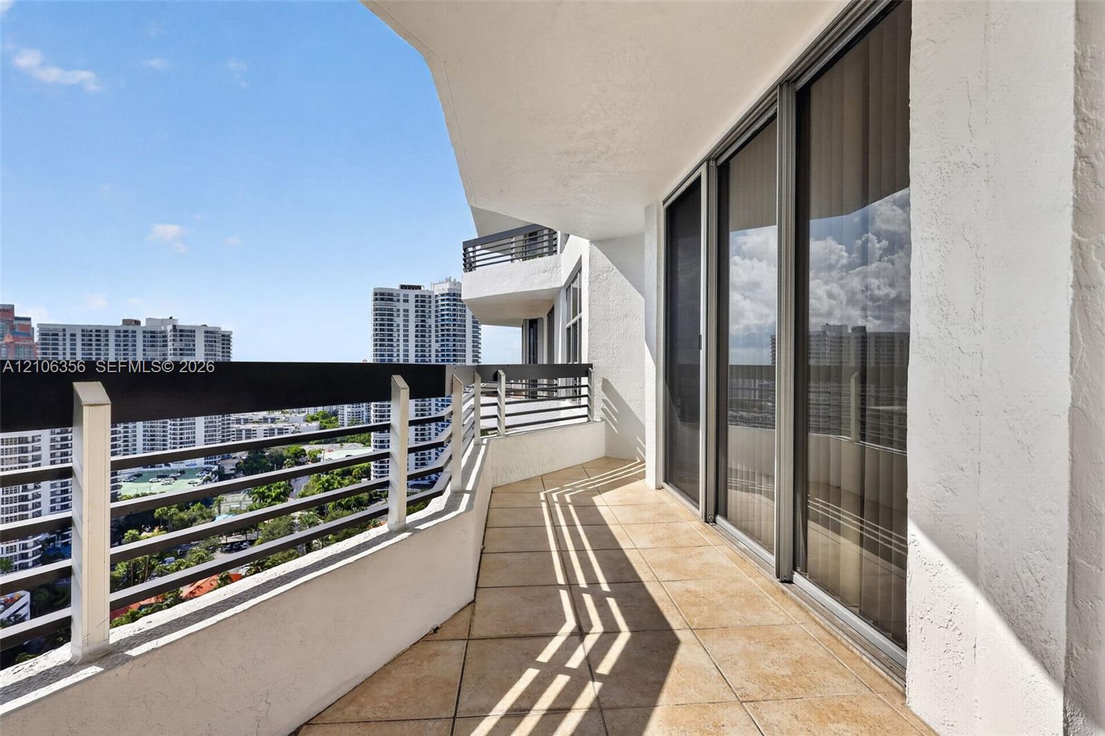 Covered balcony featuring tile flooring, metal railings, and floor-to-ceiling glass sliding doors
