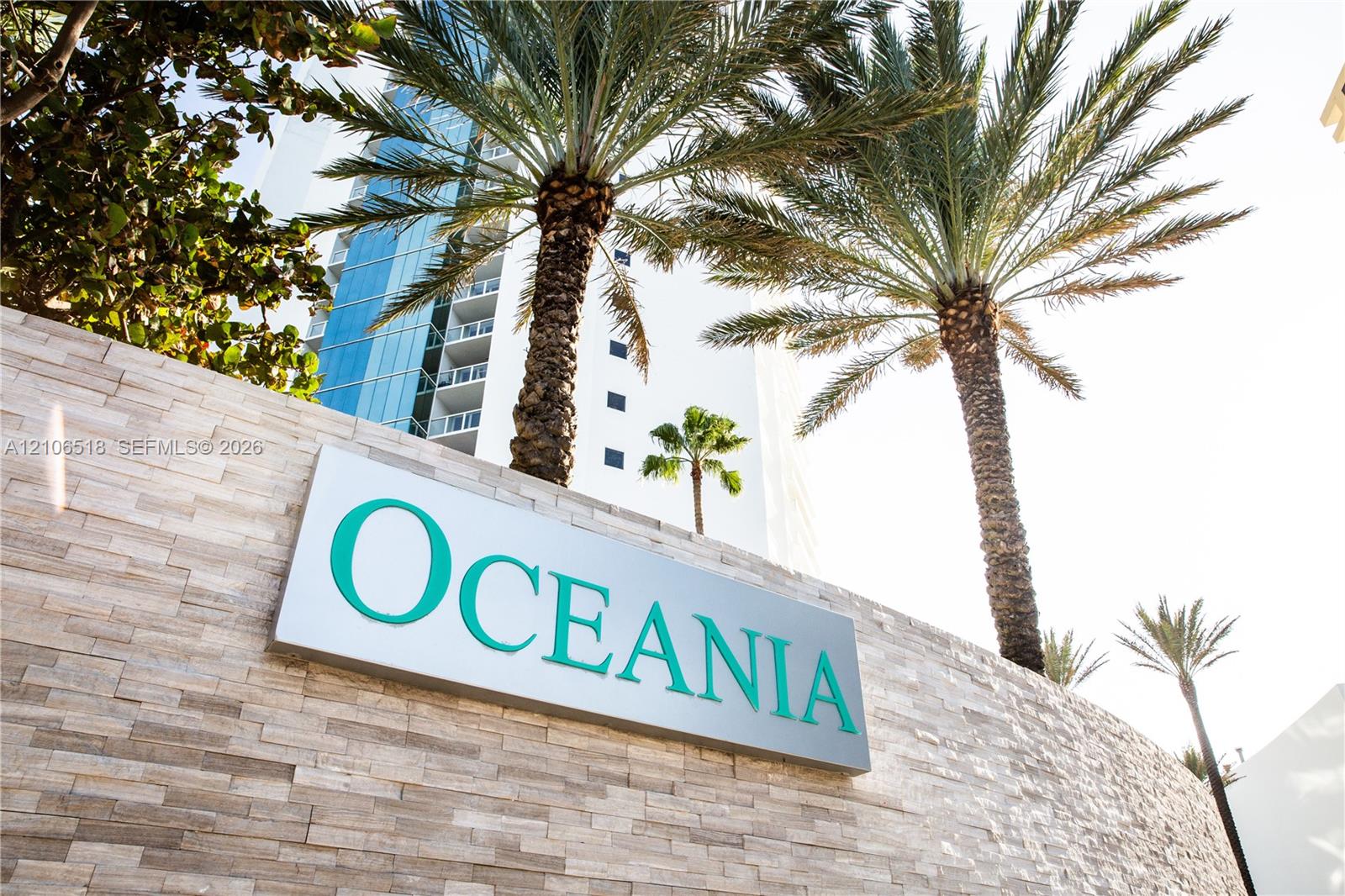Textured stone masonry wall featuring high-rise building architecture and mature palm trees