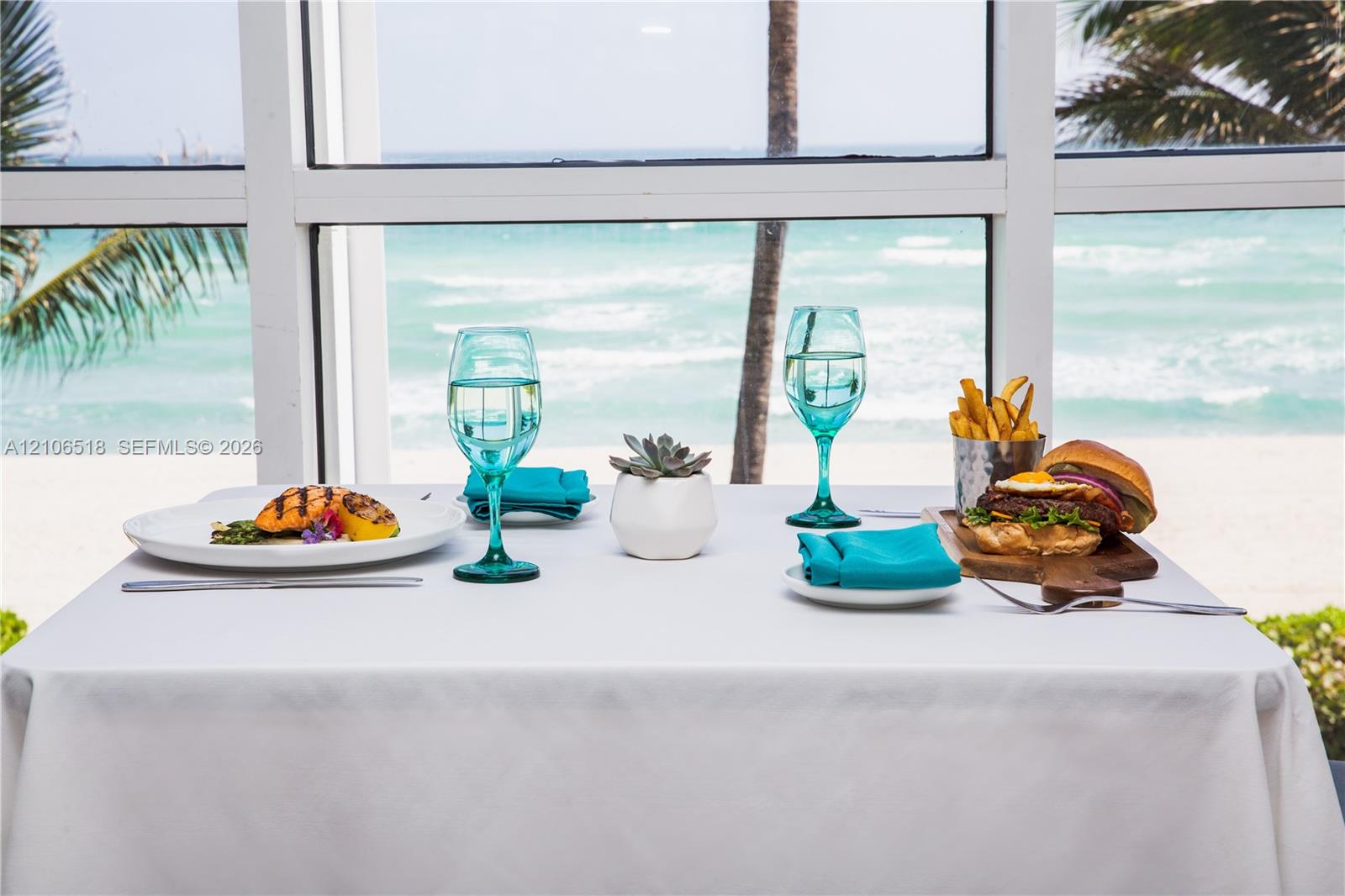 Floor-to-ceiling multi-pane windows with clear ocean and beach scenery