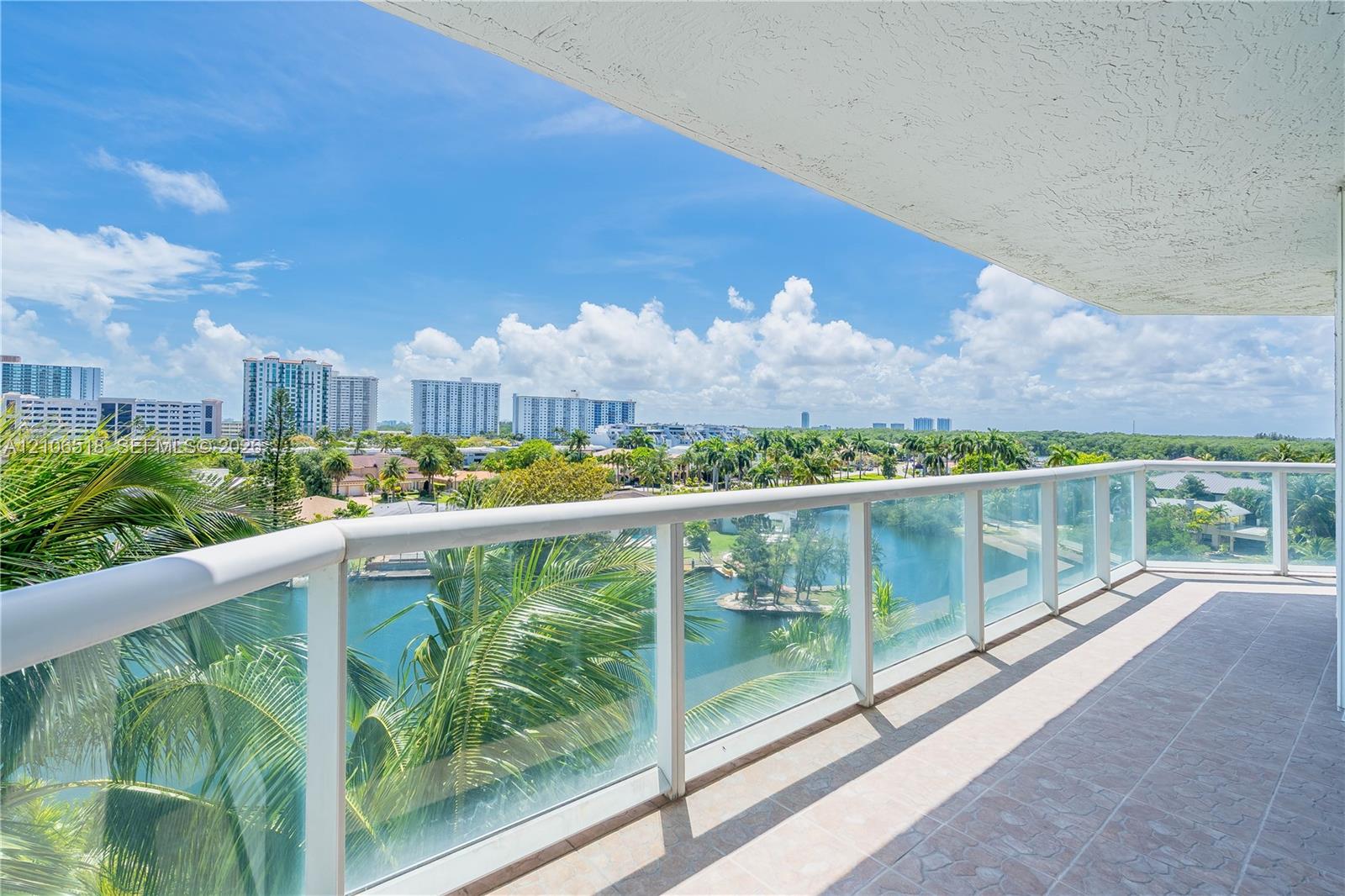 Covered balcony featuring tile flooring and a glass-paneled railing overlooking the water