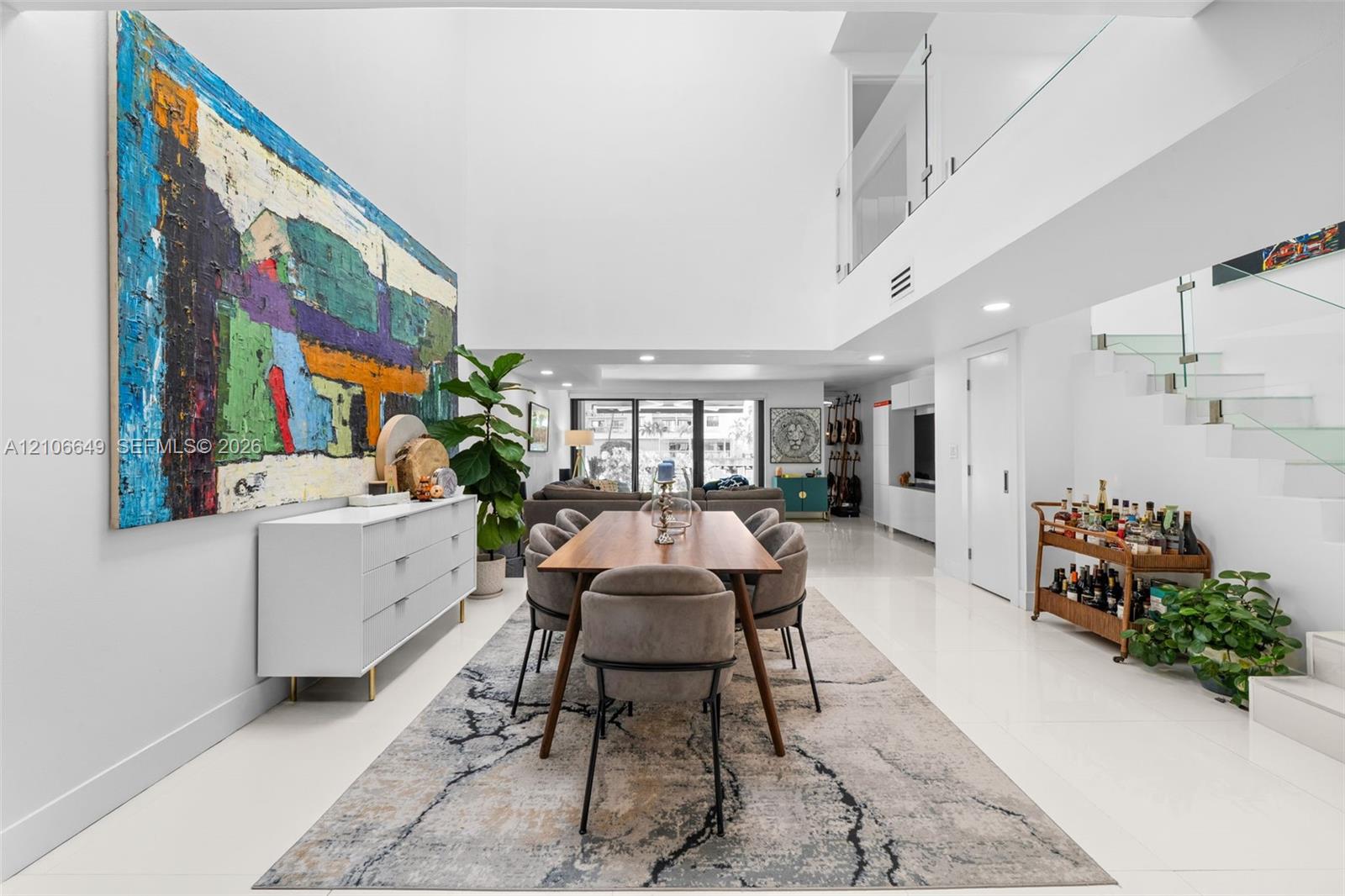 Double-height ceilings, polished tile flooring, floating staircase with glass railings, recessed lighting, and expansive wall space