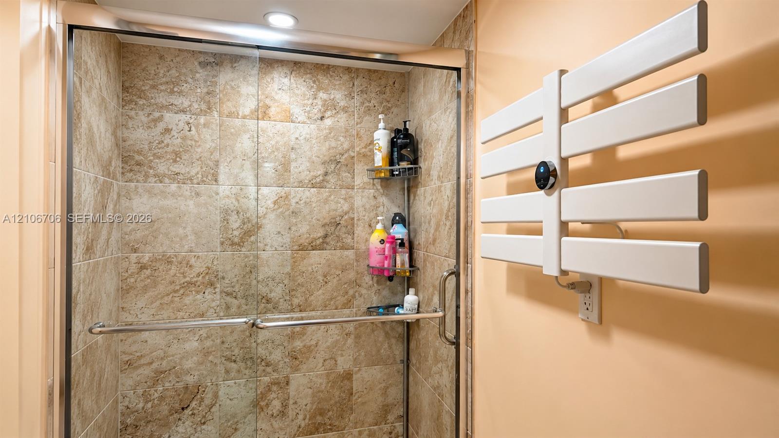 Walk-in shower featuring tile walls, a glass enclosure, and a wall-mounted electric towel warmer