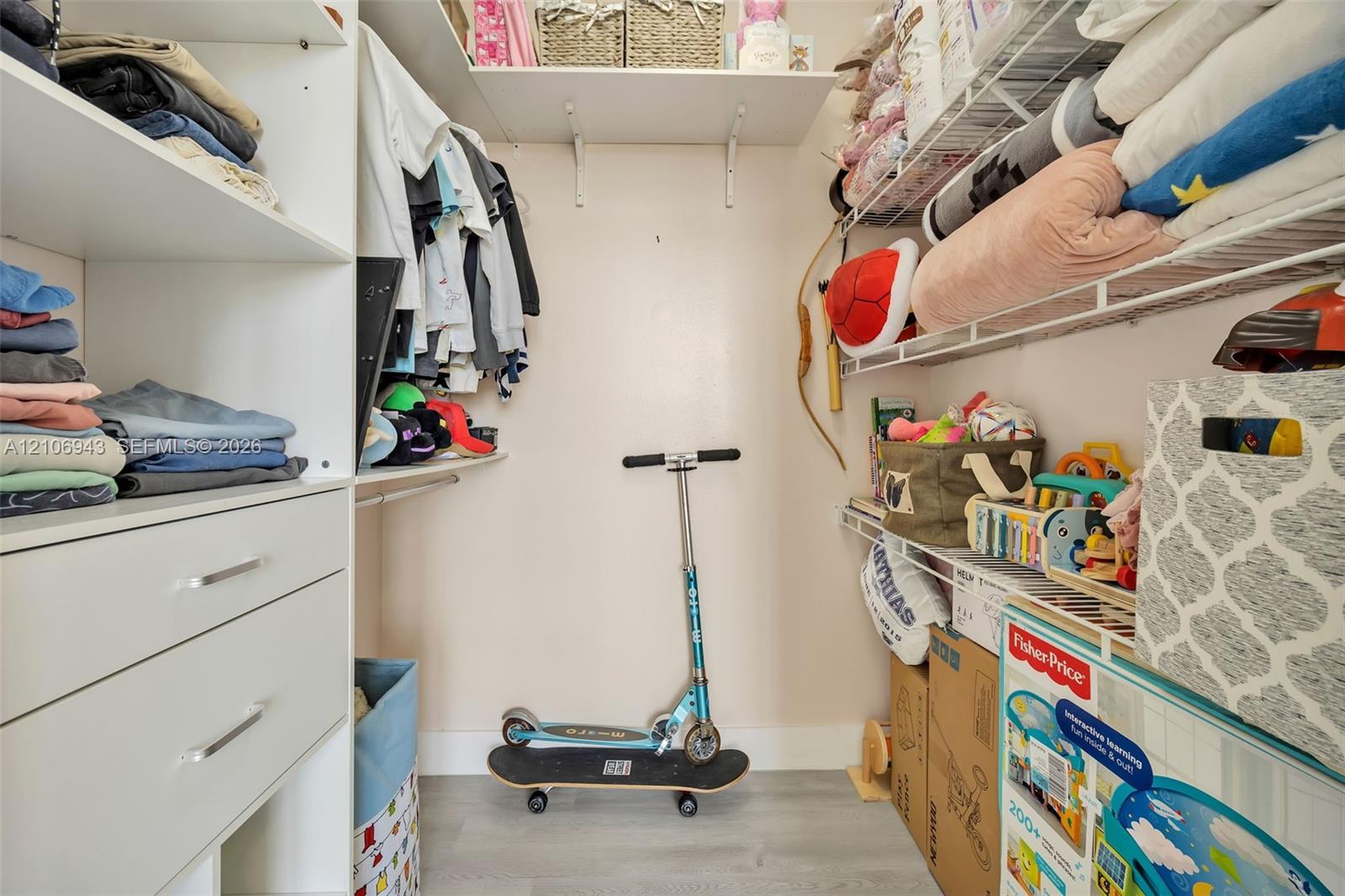 Walk-in closet featuring white built-in shelving, integrated storage drawers, and wire rack shelving systems