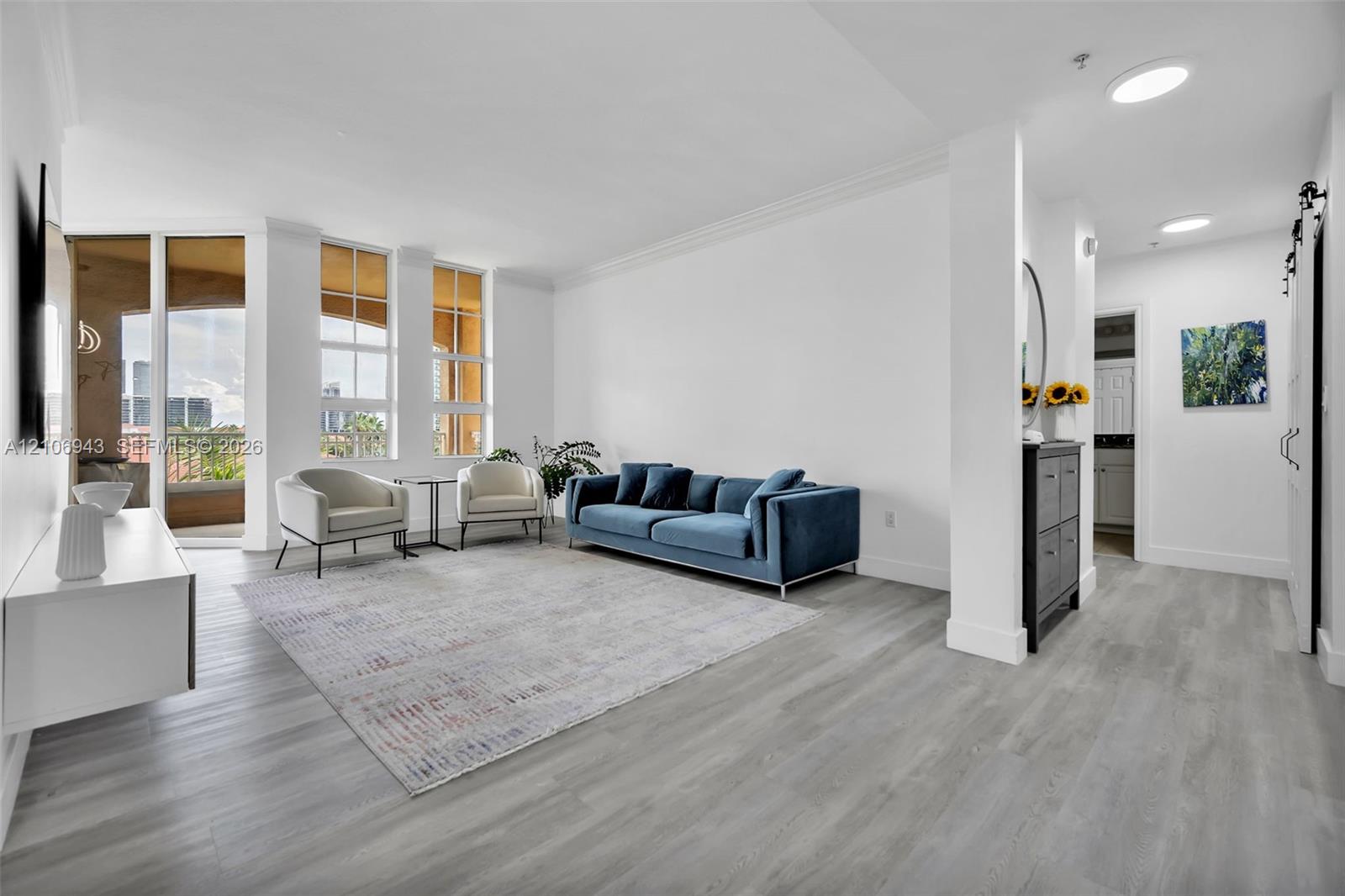 Open-concept living space featuring wood-finish flooring, floor-to-ceiling windows, recessed lighting, crown molding, and a sliding barn door